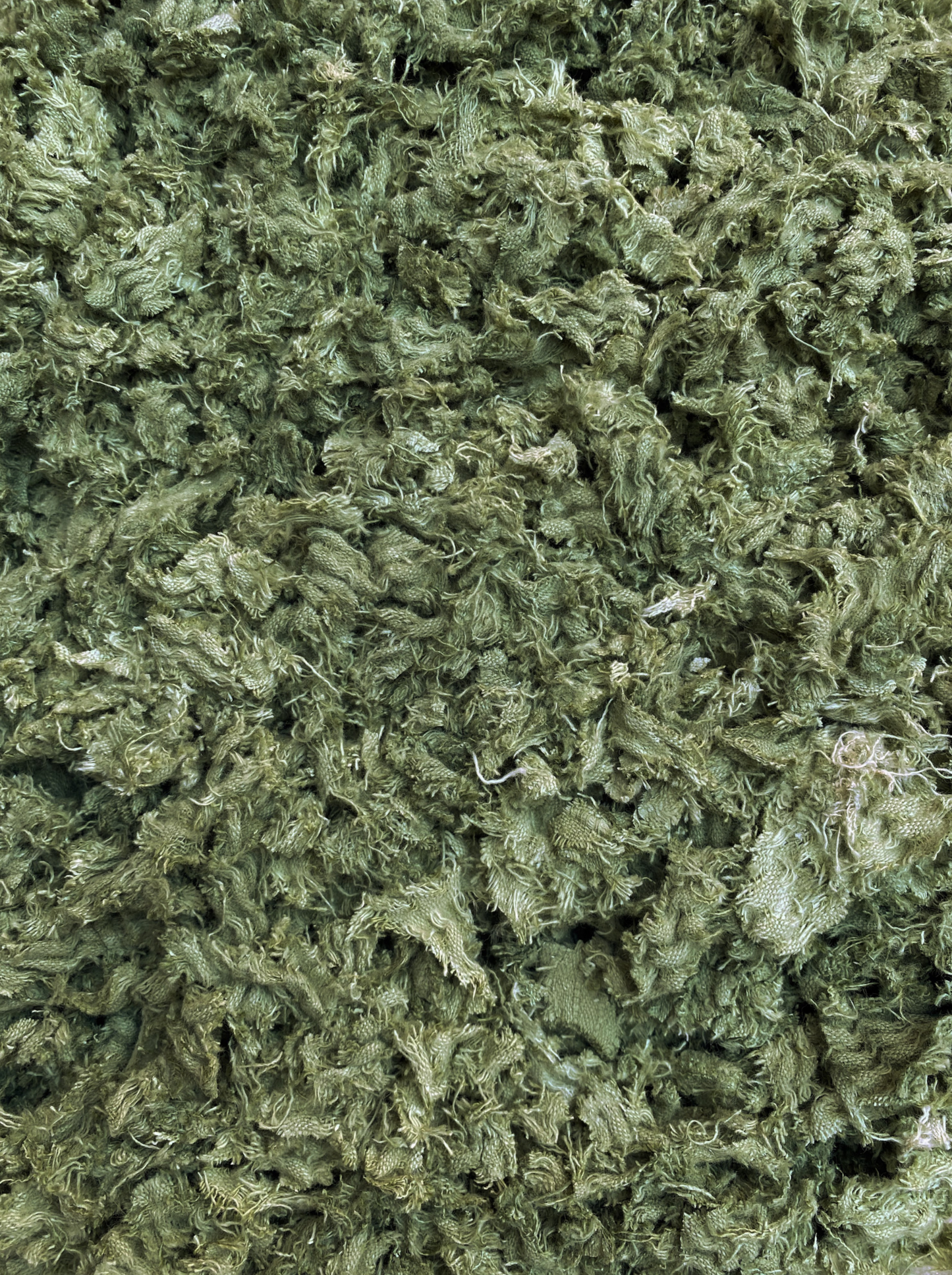 A close-up image of pistachio green shredded textile material.