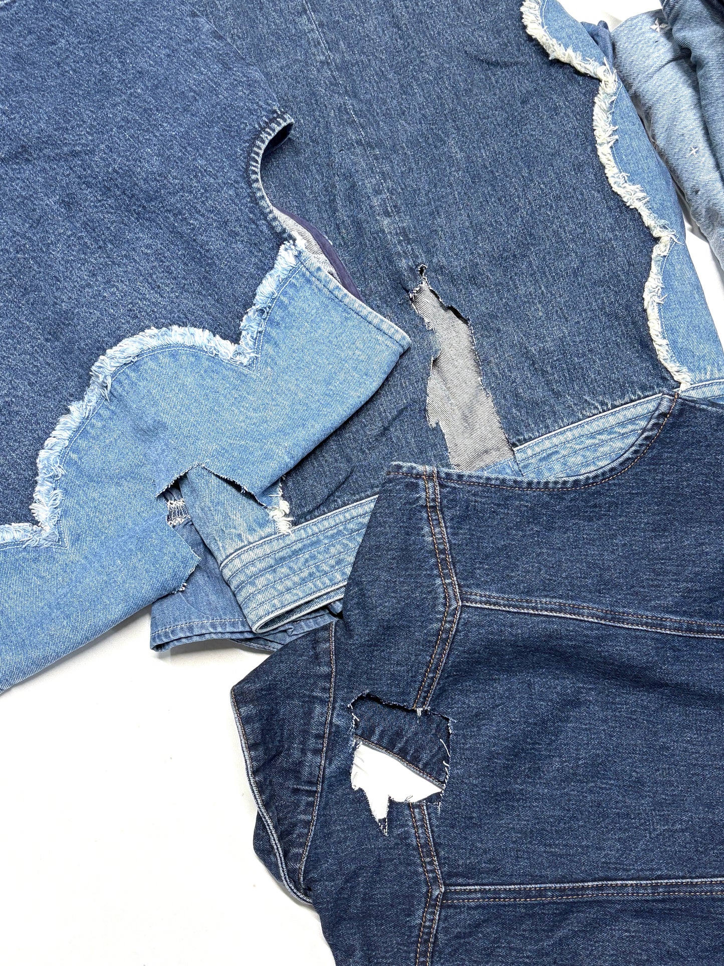 Stack of distressed denim jeans on a white background for upcycling, DIY and crafts projects