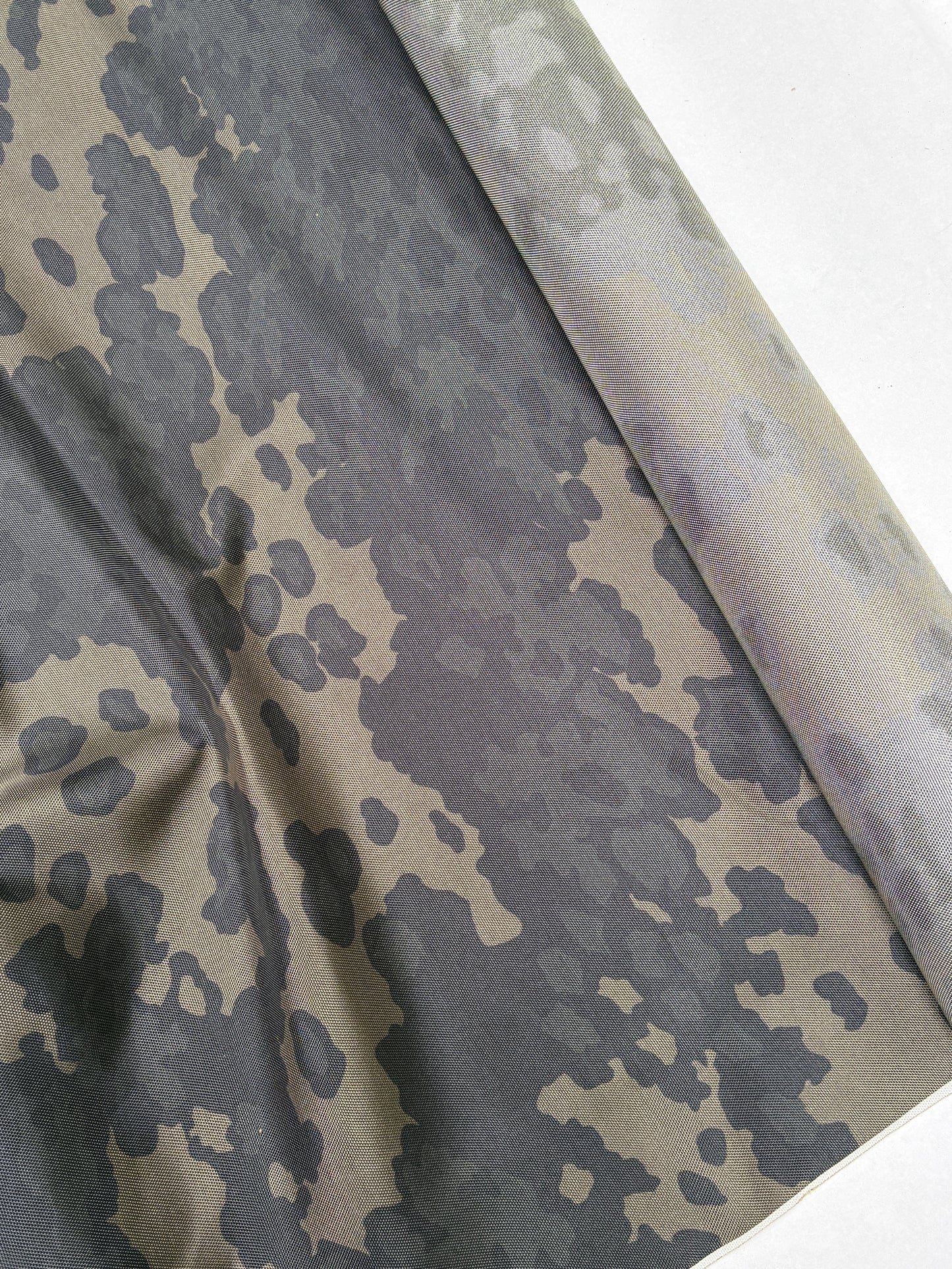 Camouflage fabric in dark green and khaki with soft folded texture.