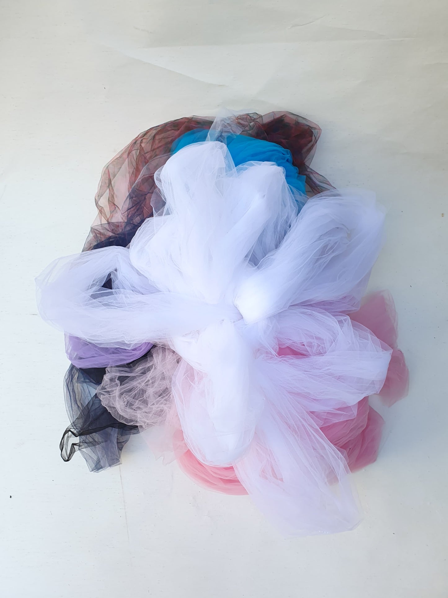Mixed tulle fabric pieces layered in soft folds on a white background.