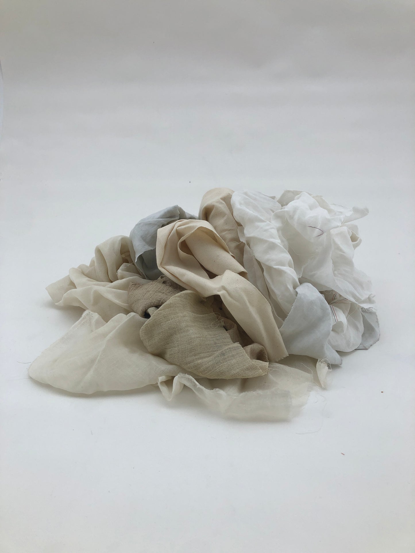 Various off-white fabrics with texture and folds on a white background