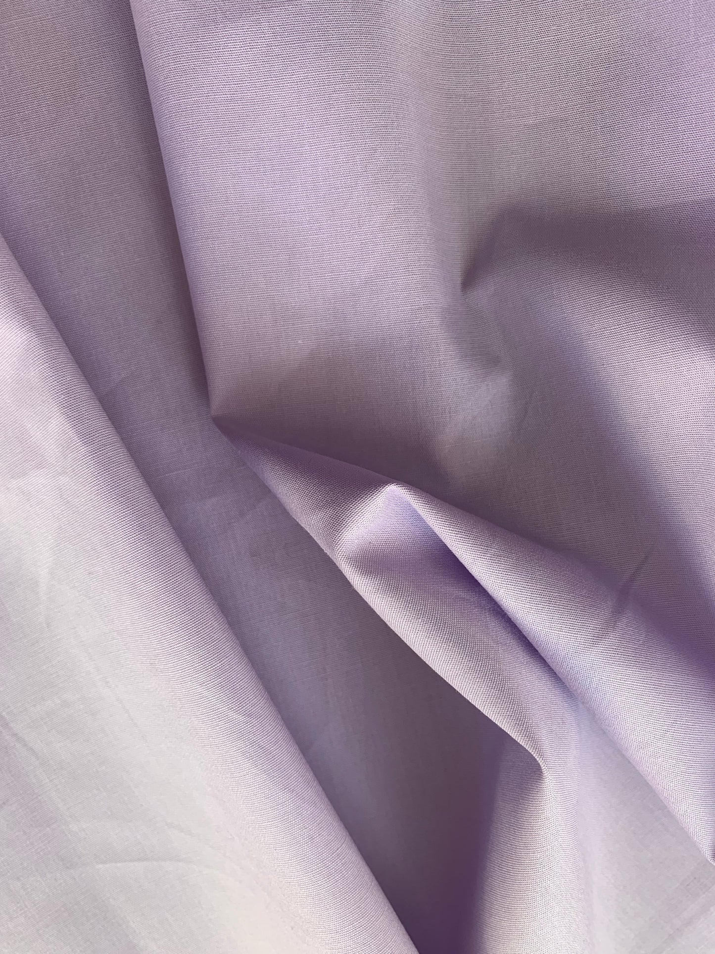 Pale purple fabric is gathered with visible smooth fold