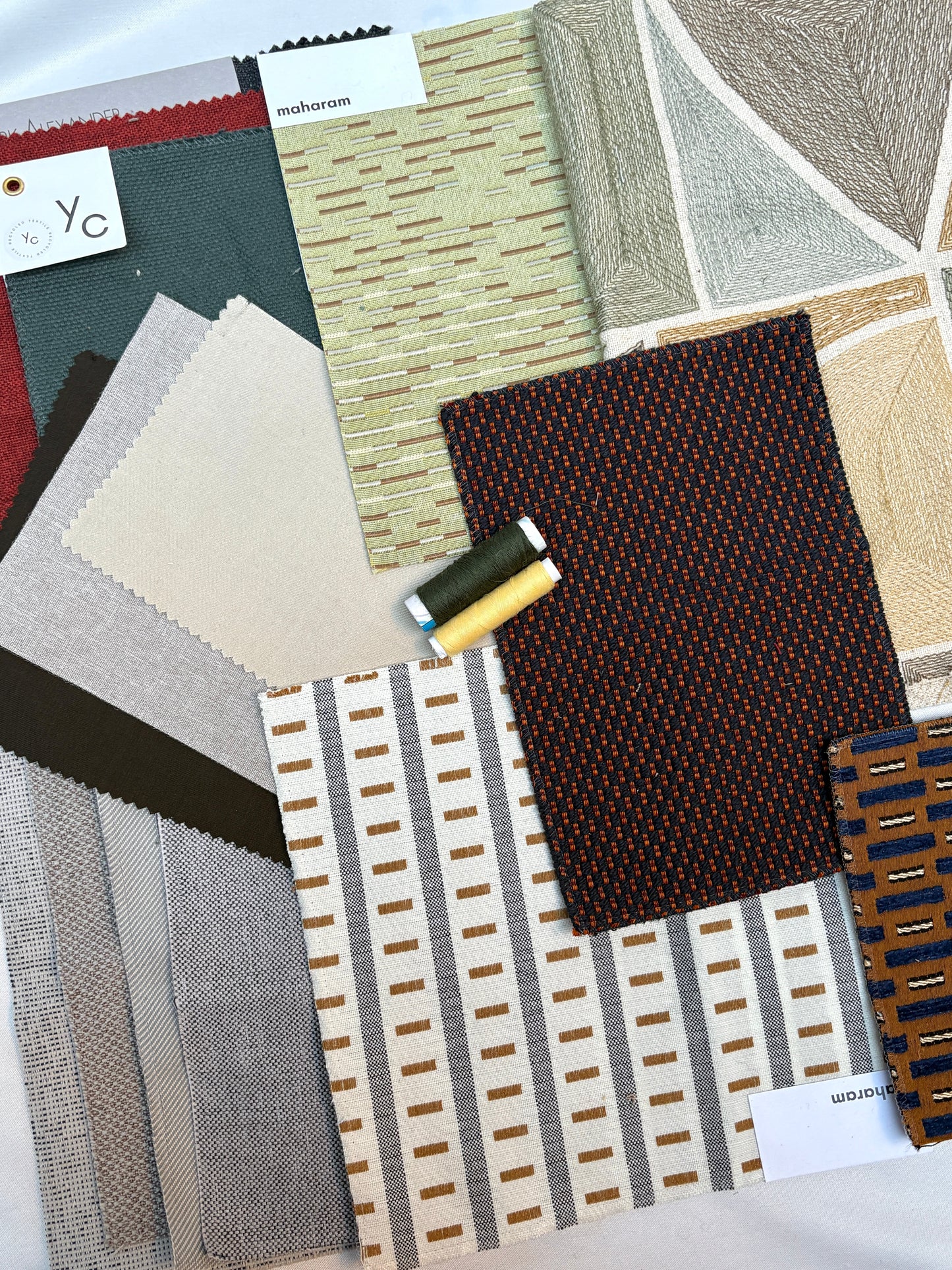 Assorted upholstery fabric swatches arranged with coordinating thread spools.