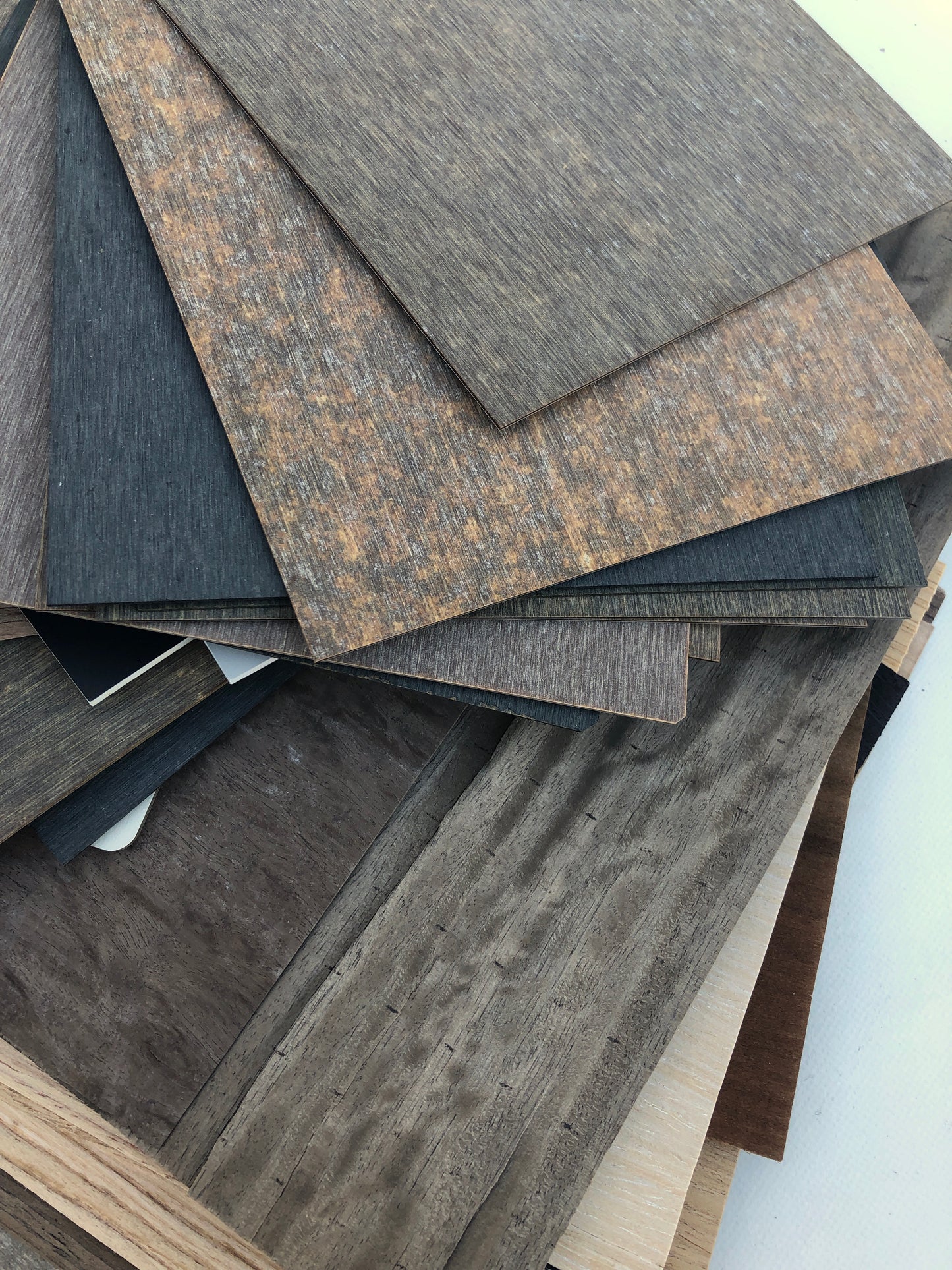 Wood-effect panels are arranged in a loose layered pile on white