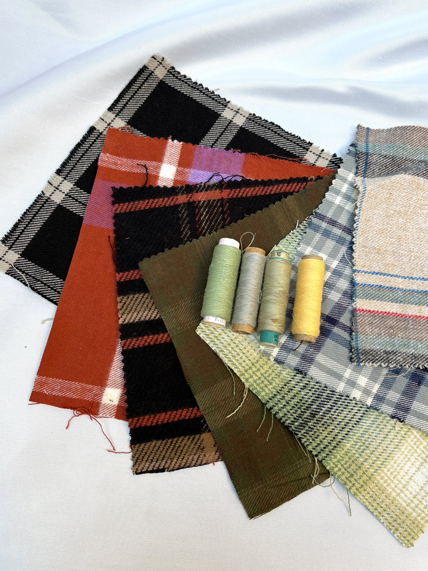Plaid fabric swatches in mixed tones with matching thread spools.