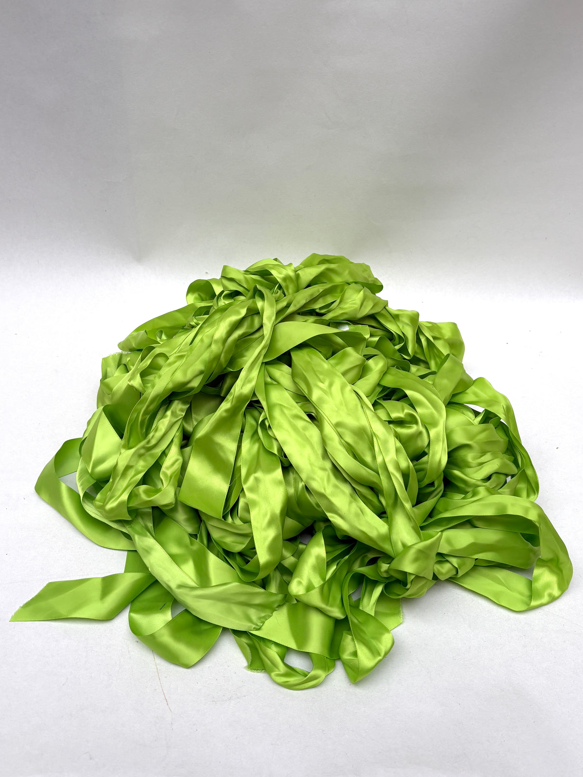 A pile of light green satin ribbons on a white background.