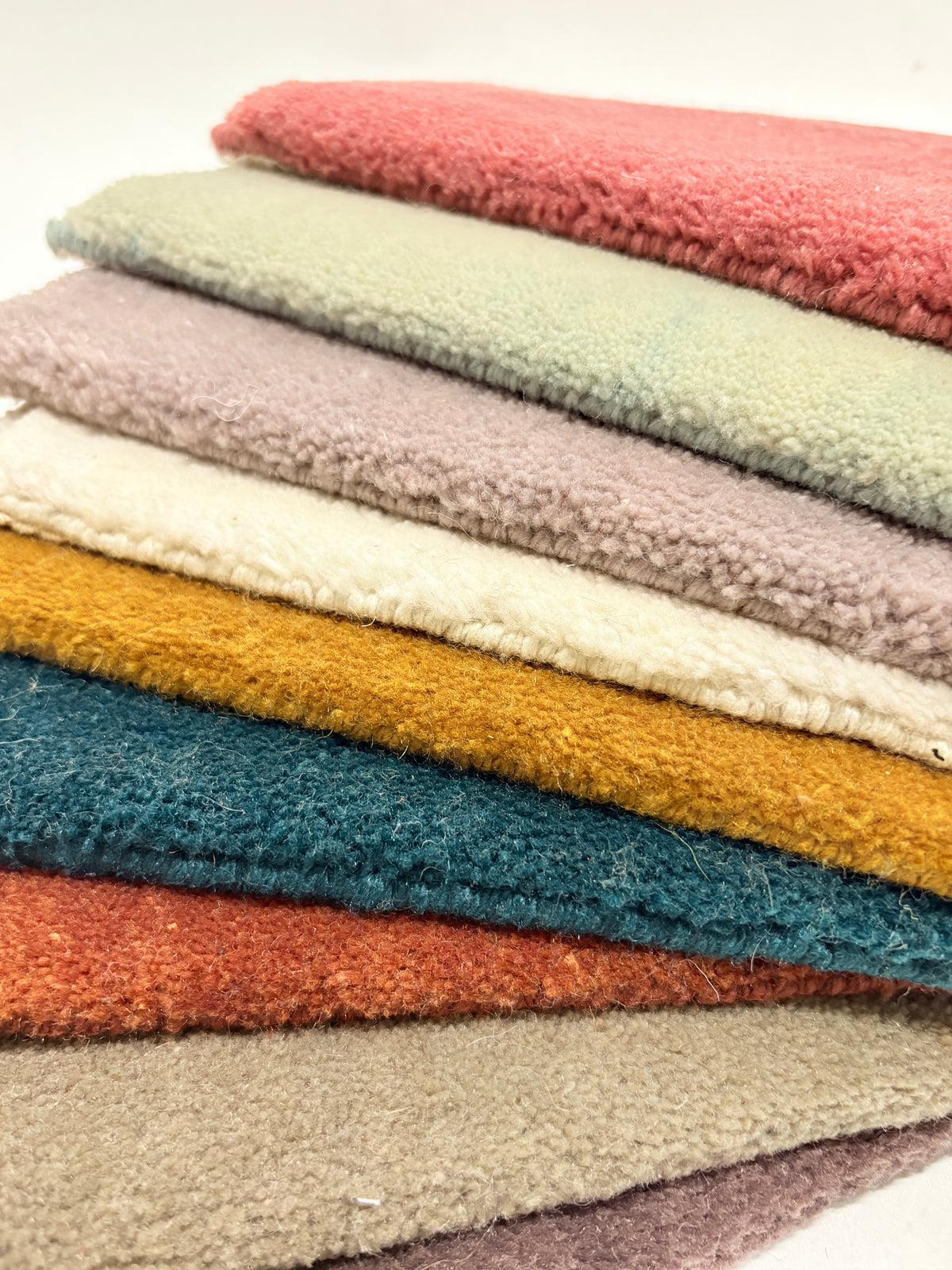 Close-up shots of multi-layered velvet fabric samples in various colors and with a soft, fluffy texture.