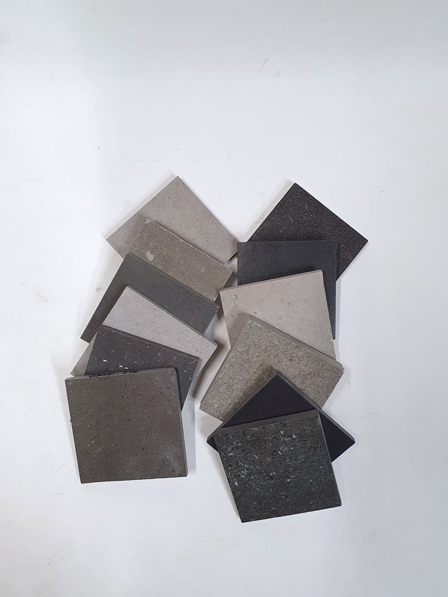 Assorted grey tile samples arranged on a white background.