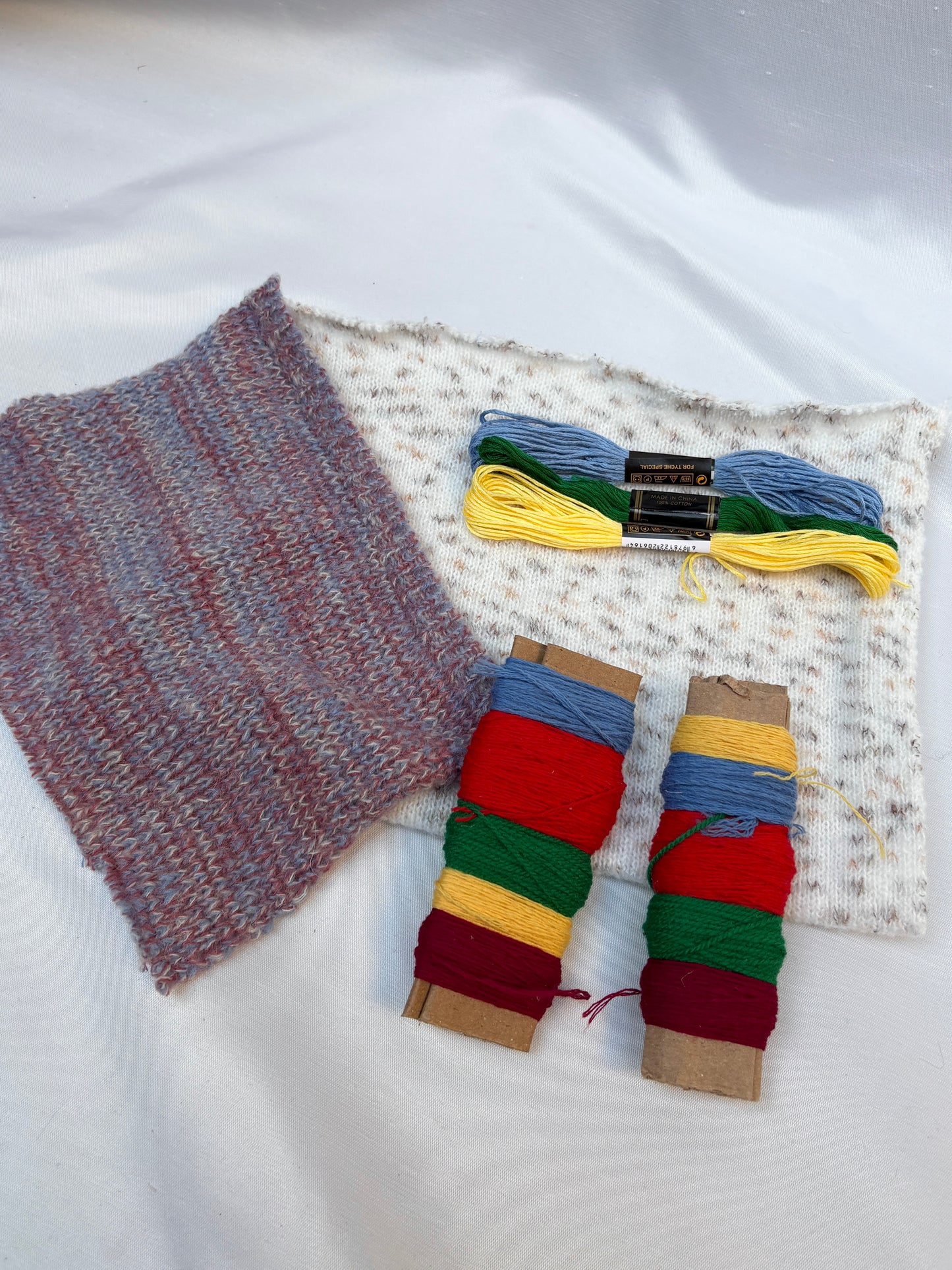 Soft fabric swatches paired with colourful thread spools and embroidery floss.