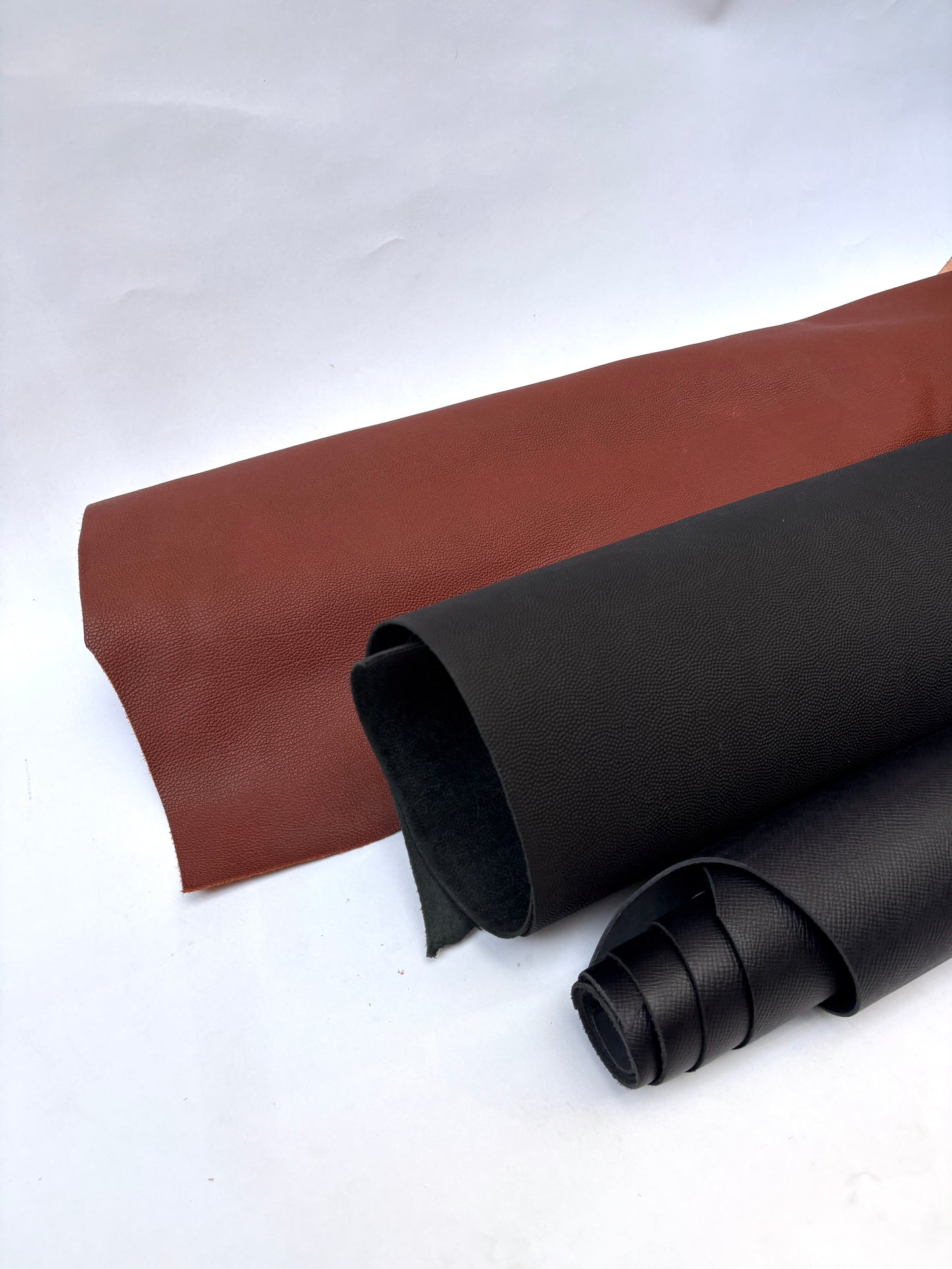 Two rolls of brown and black leather
