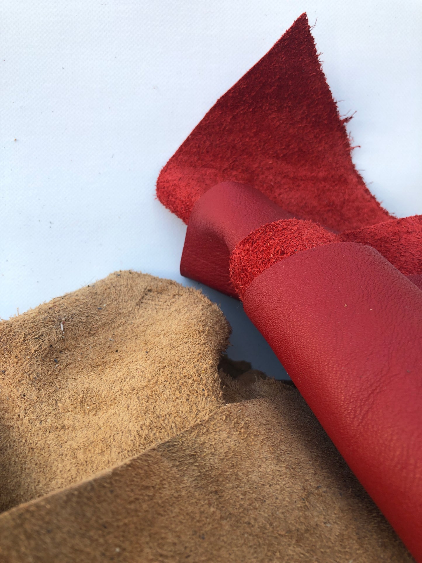Close-up of offcuts of leather with red and brown, soft texture visible