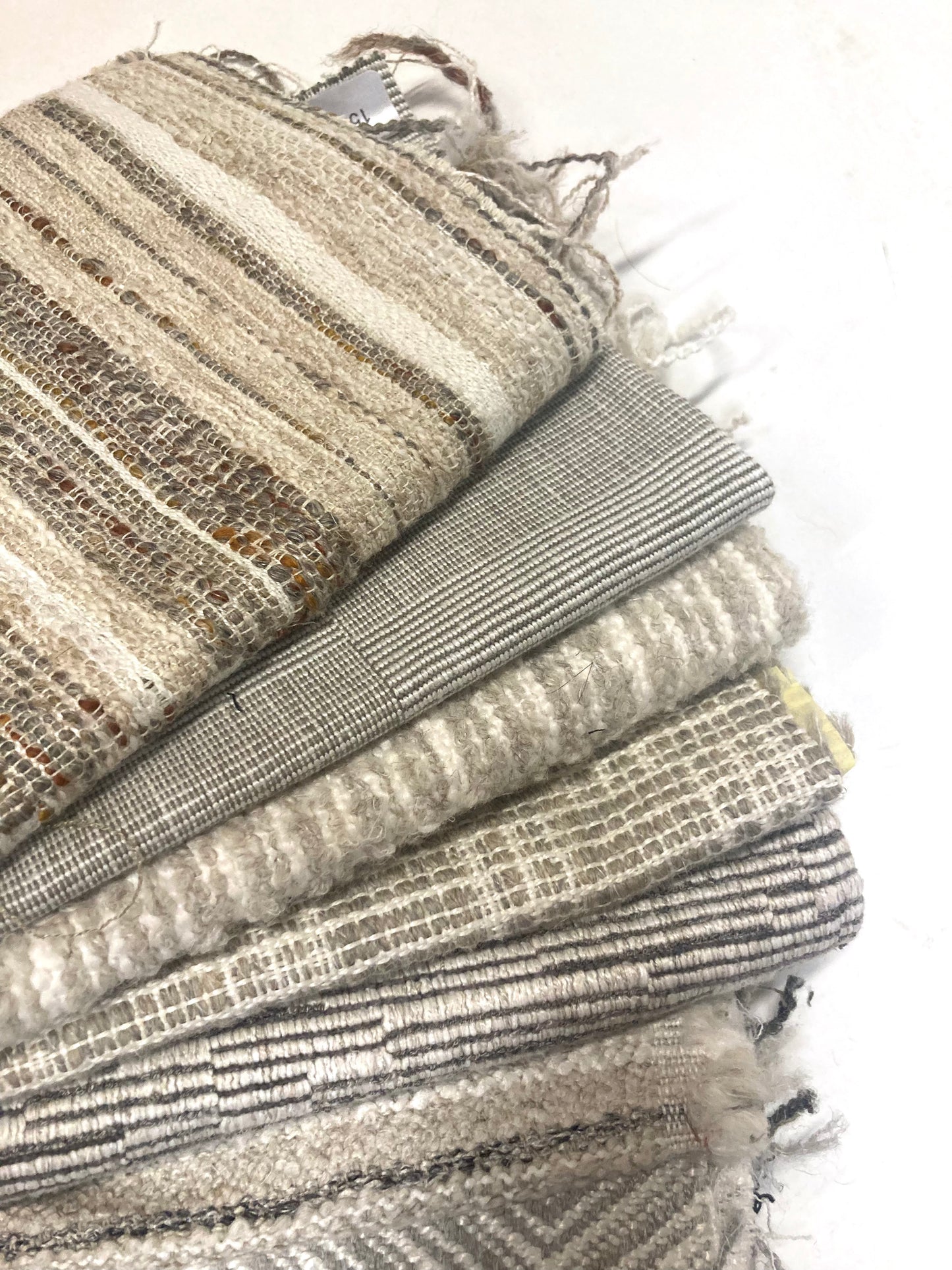 Close-up of several neutral coloured heavyweight fabric, texture visible