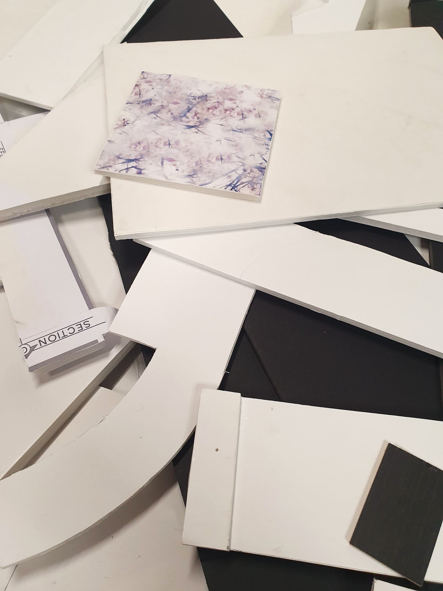 A collection of black and white foam board offcuts of various sizes with a patterned square plastic foam board