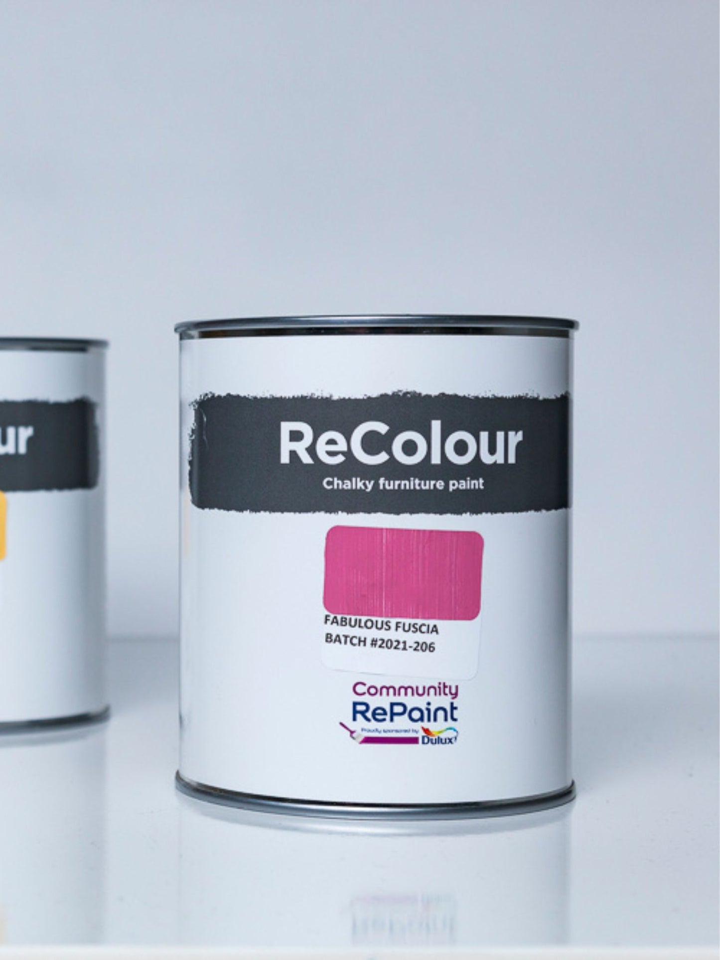 Close up of two cans of ReColour acrylic chalky furniture paint, one can paint colour named "fabulous fuscia"