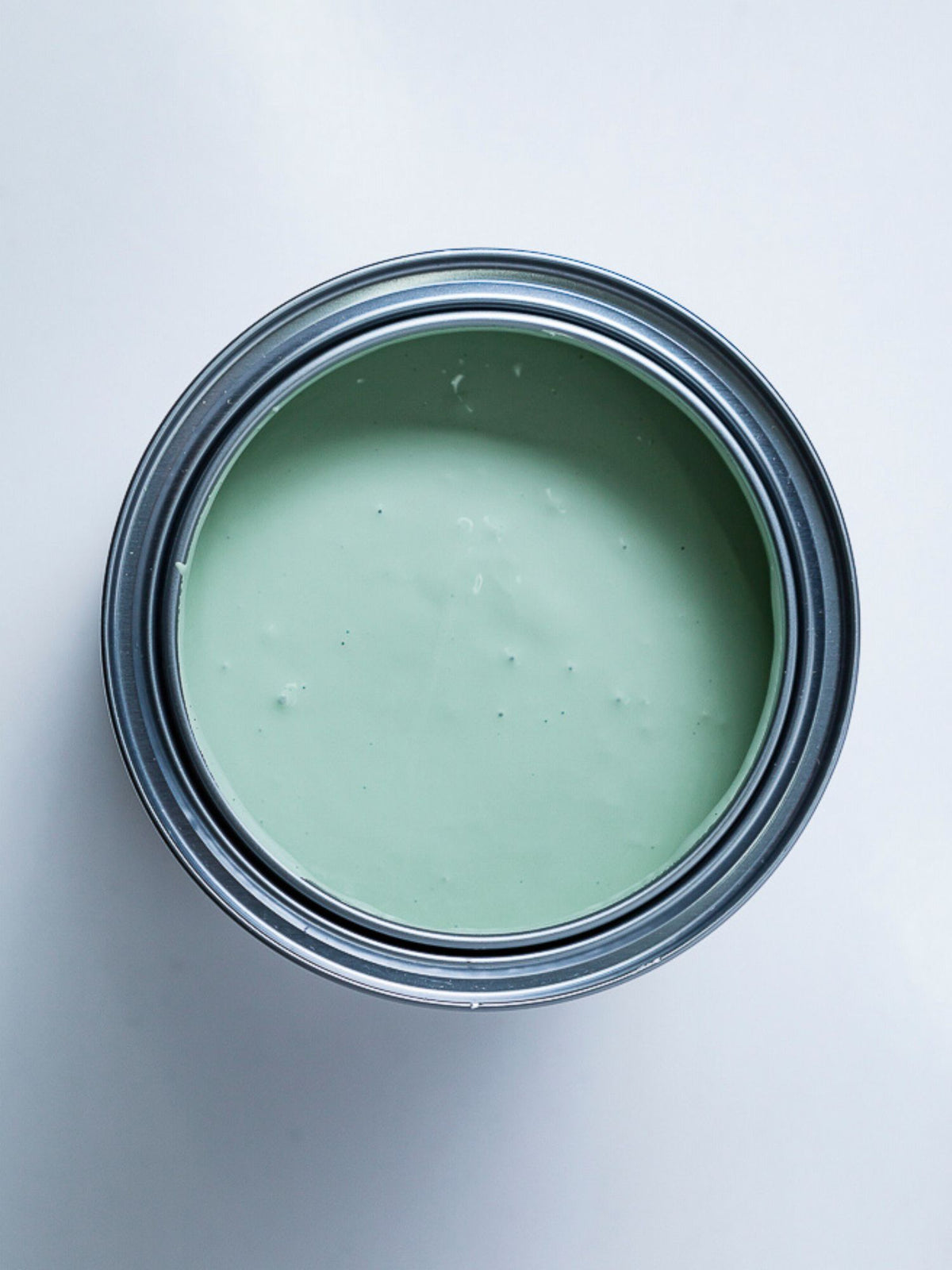 Top view of an open can of light green paint.