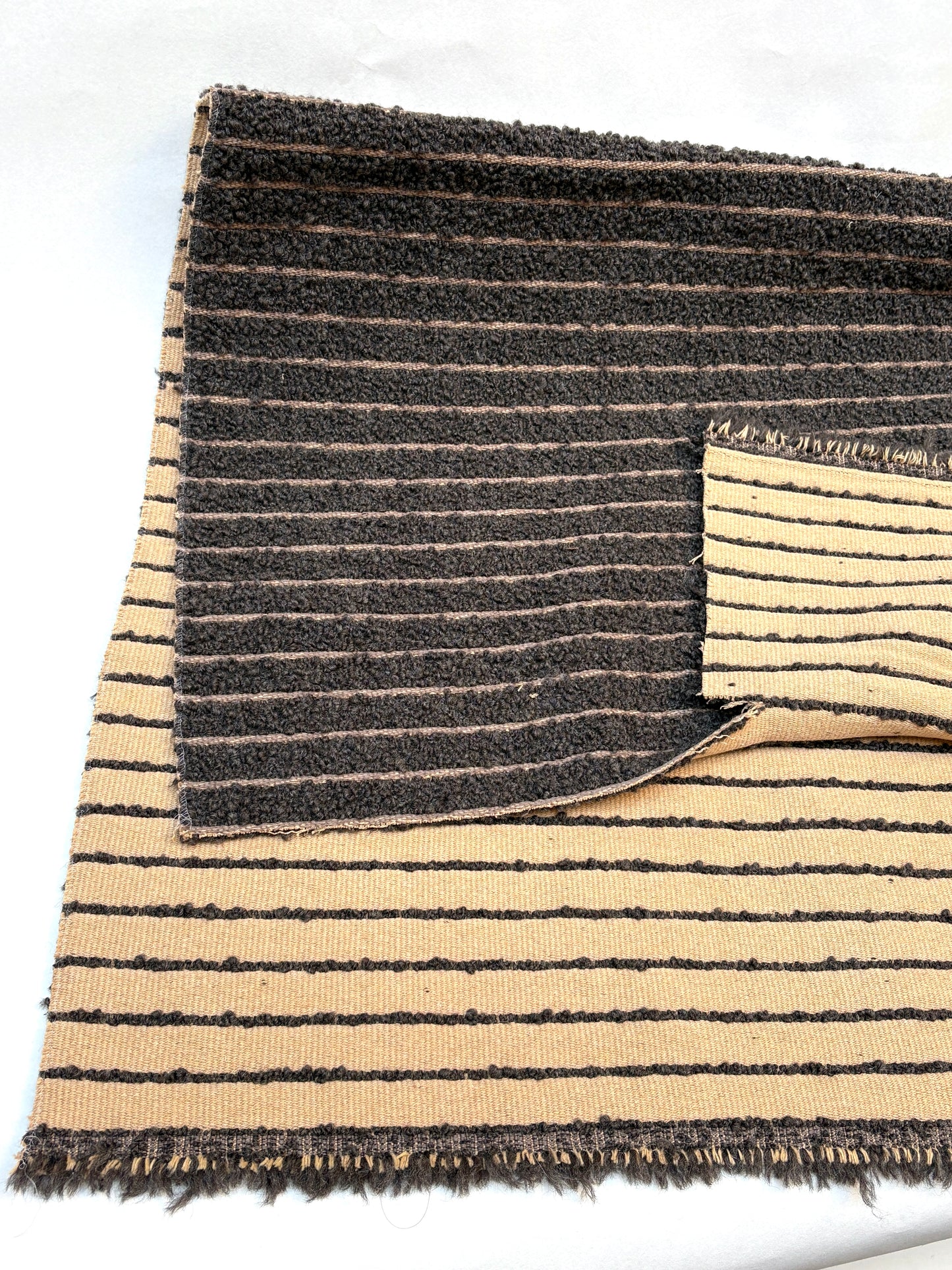 Layered striped fabric pieces in brown and cream on a white background.