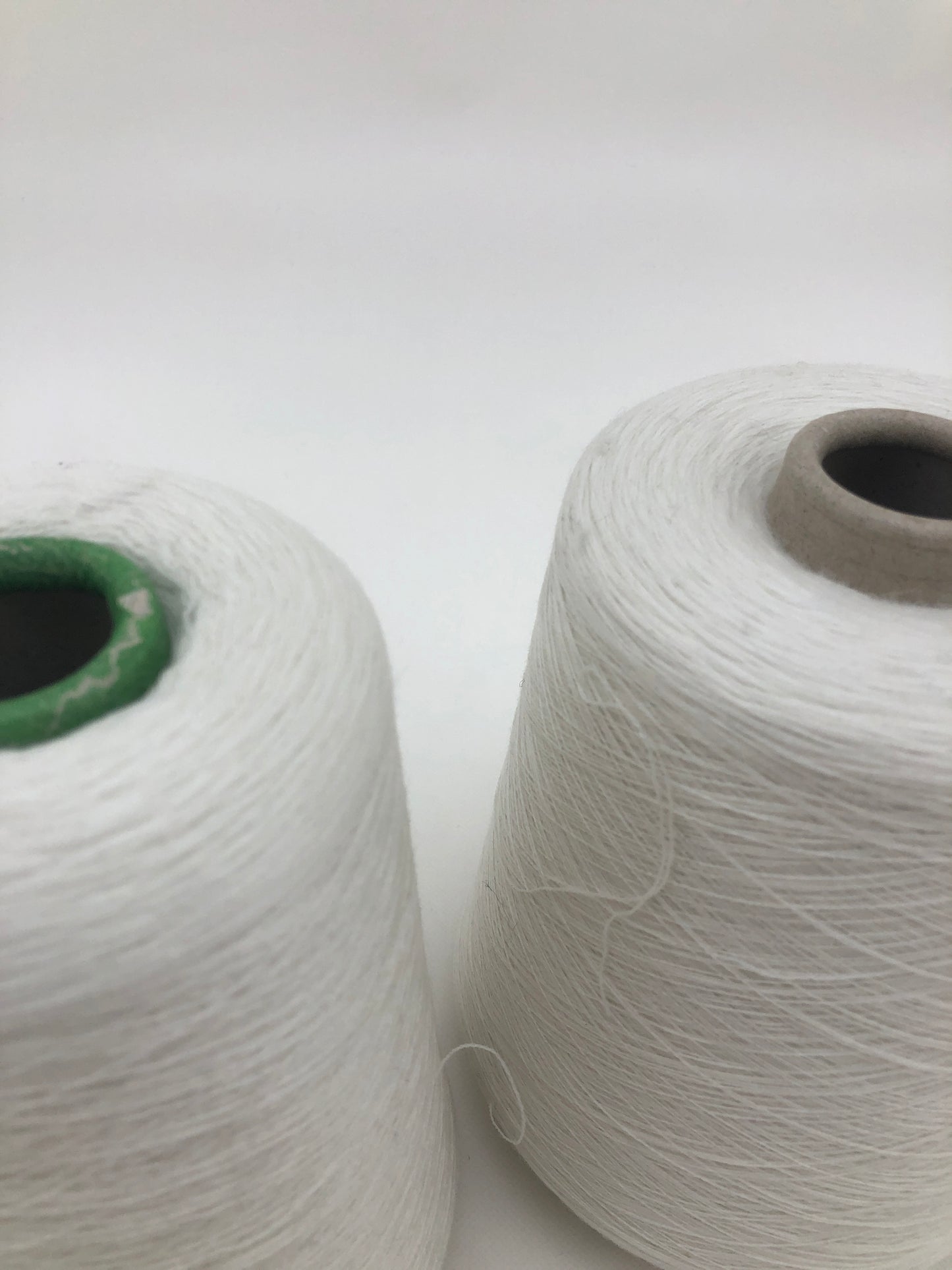 Close up of two cones of white yarn from its top.