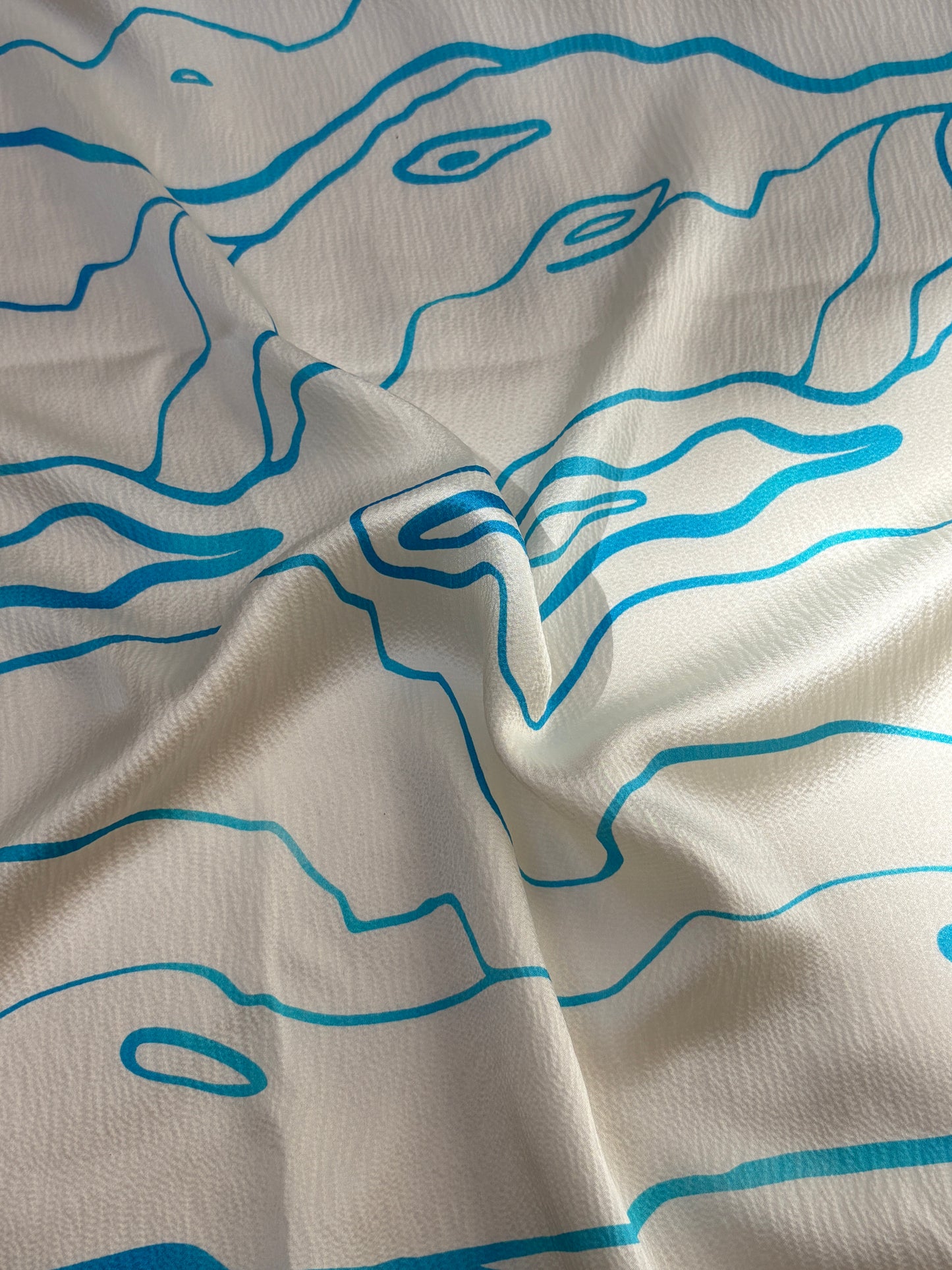 Silk fabric with blue abstract line patterns on a beige background