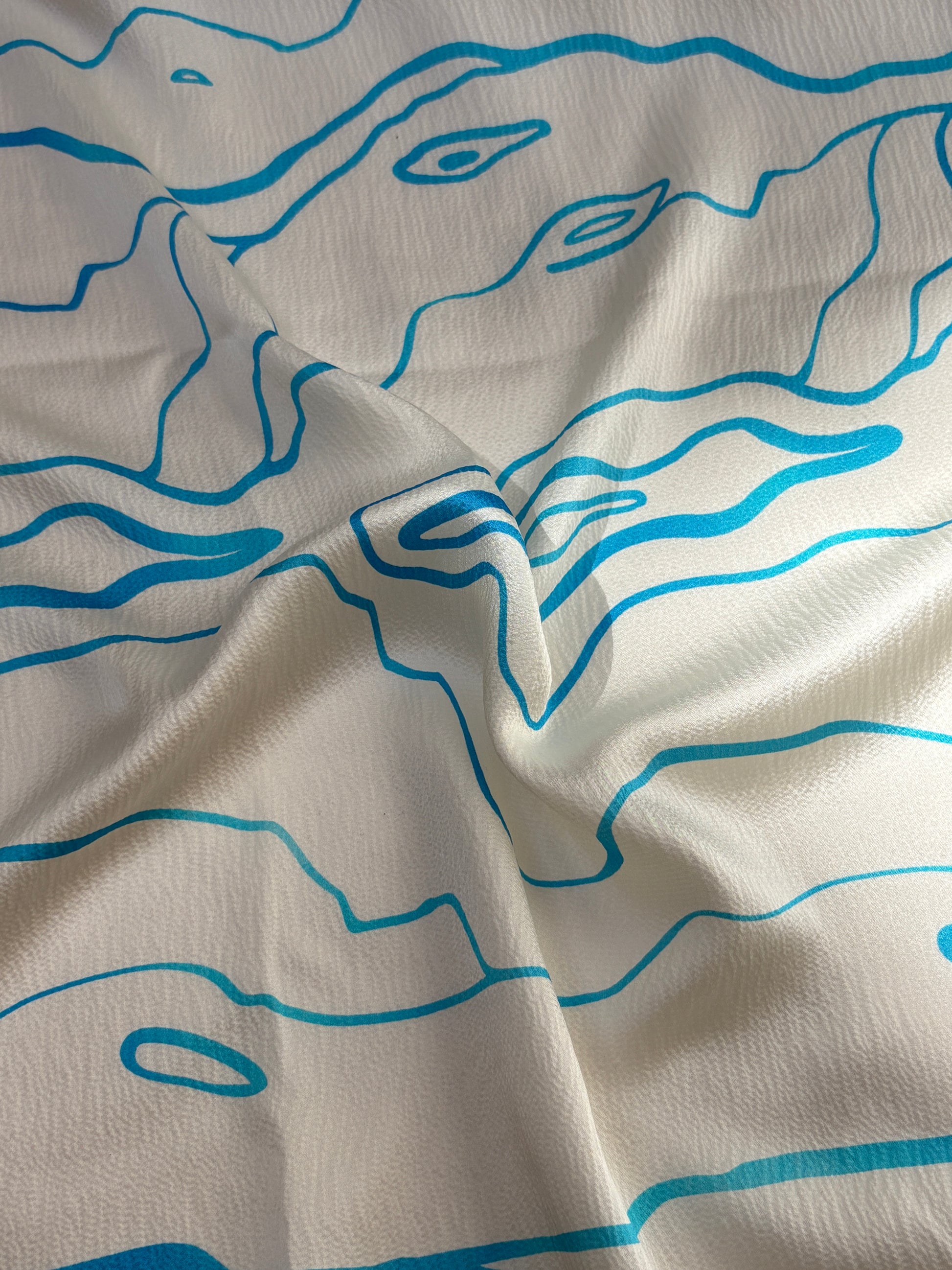 Silk fabric with blue abstract line patterns on a beige background