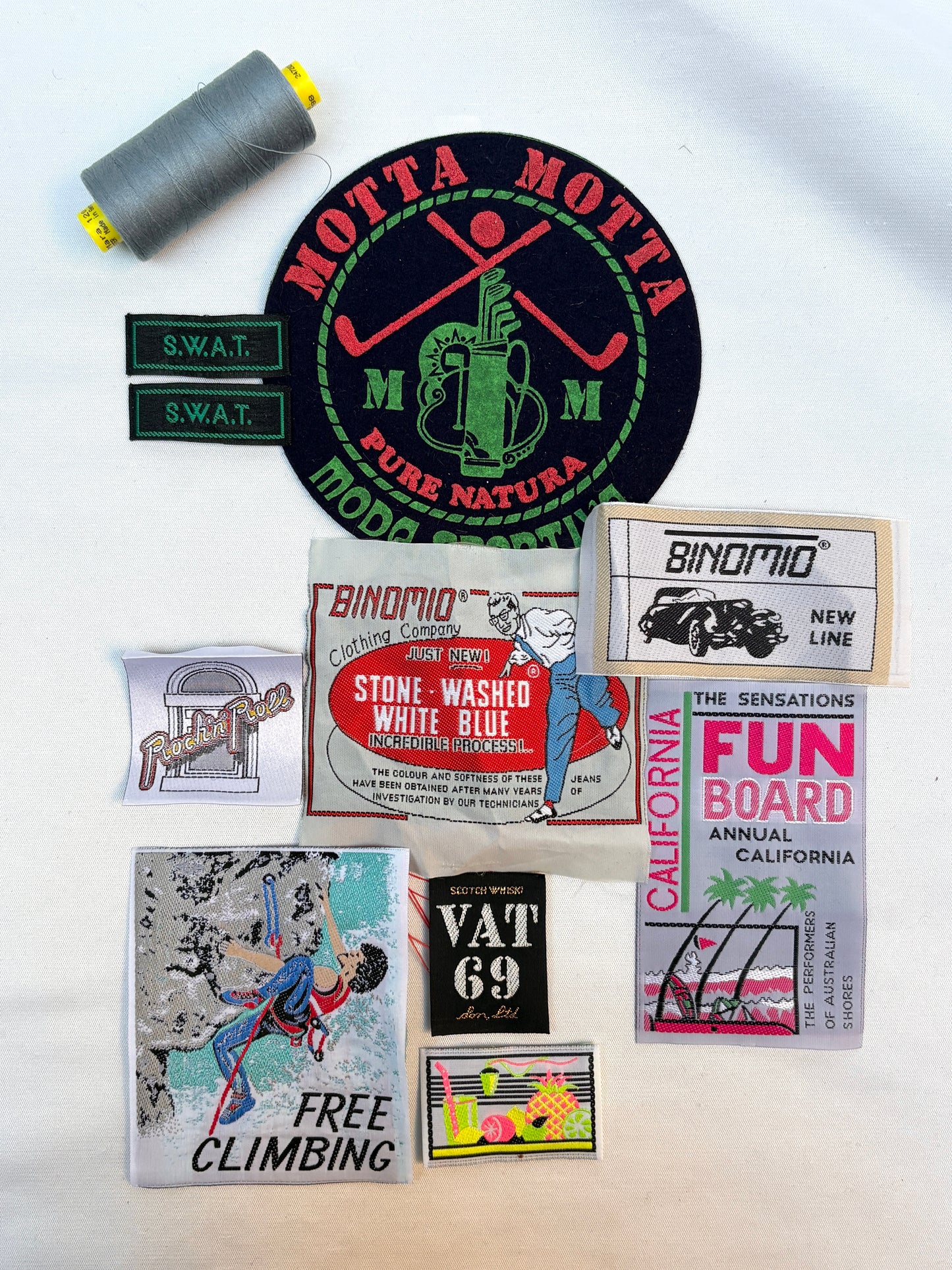 Collection of vintage-style product labels and a spool of thread on a white background