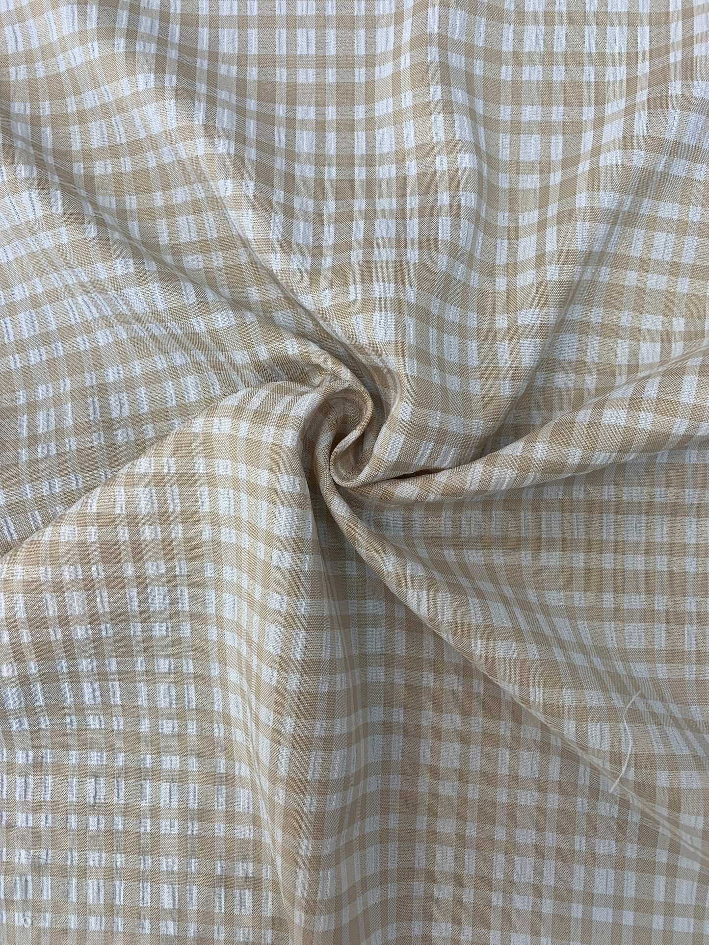 Textured close-up of apple check deadstock fabric in stone and white.
