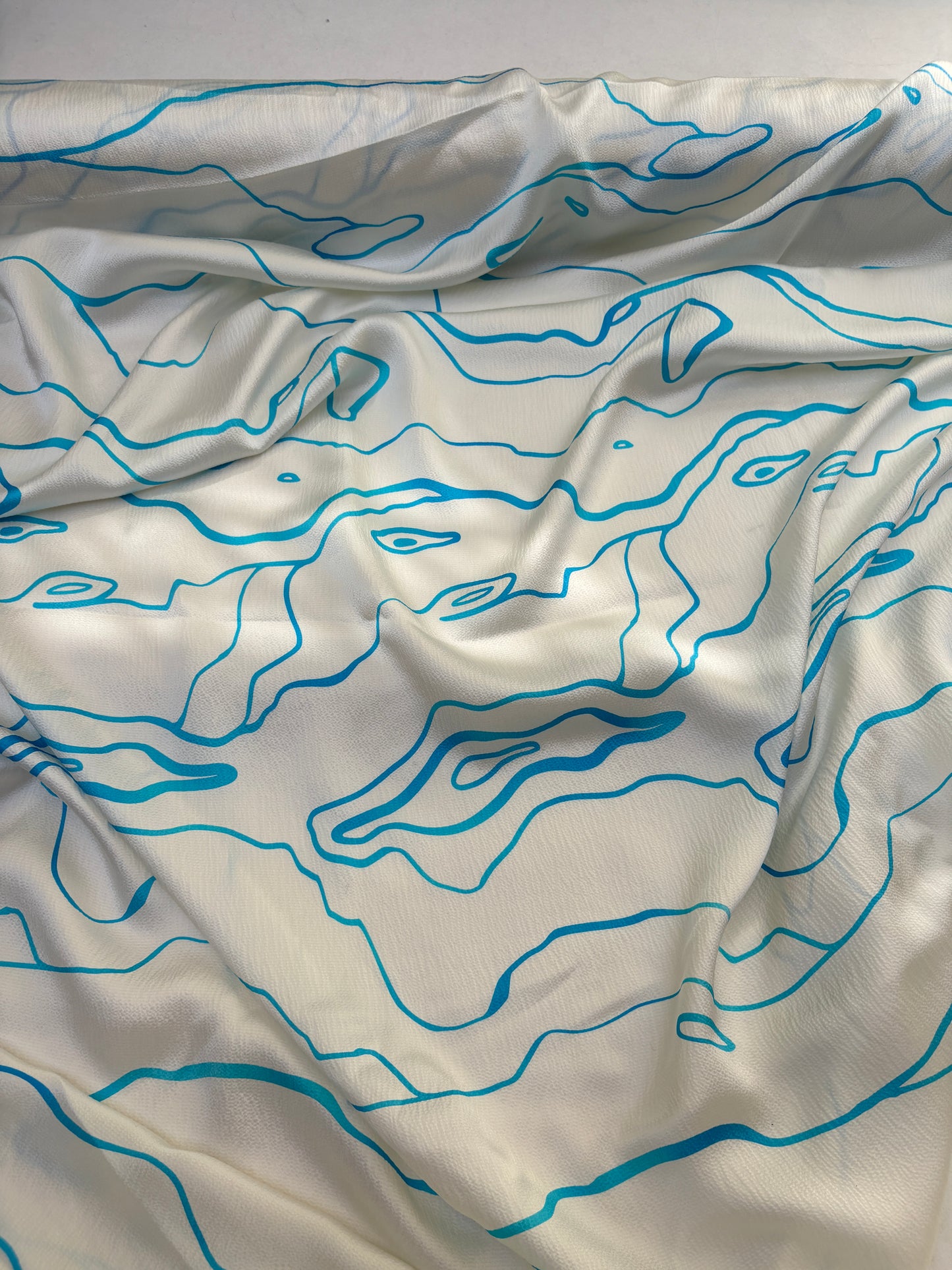 White silk fabric with blue abstract line patterns on a plain background
