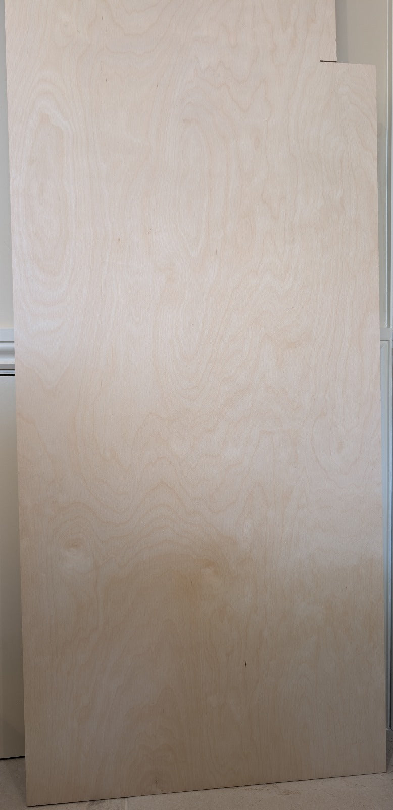 The bottom part of the reclaimed birch plywood sheet with a visible grain pattern, with marks of previous use on the top right.