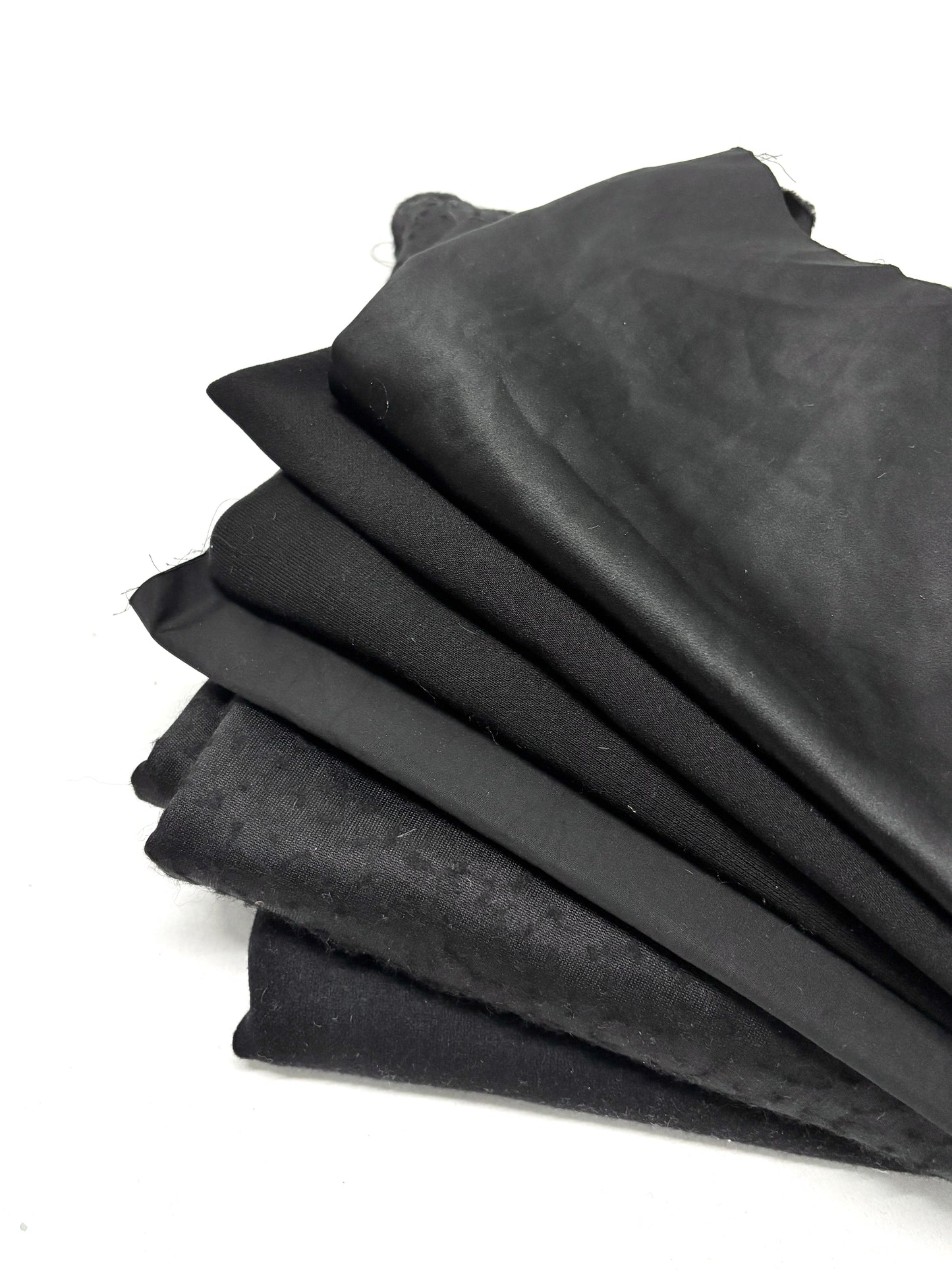 Stack of black fabrics in various textures 