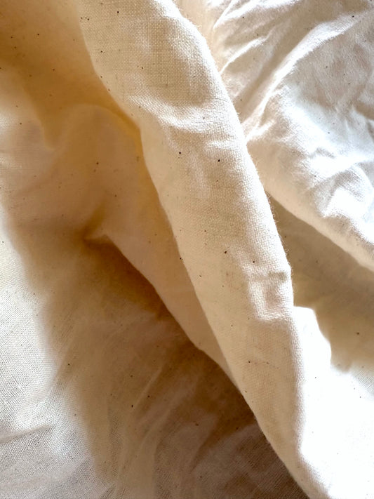 Softly piled off-white cotton calico fabric in natural folds.