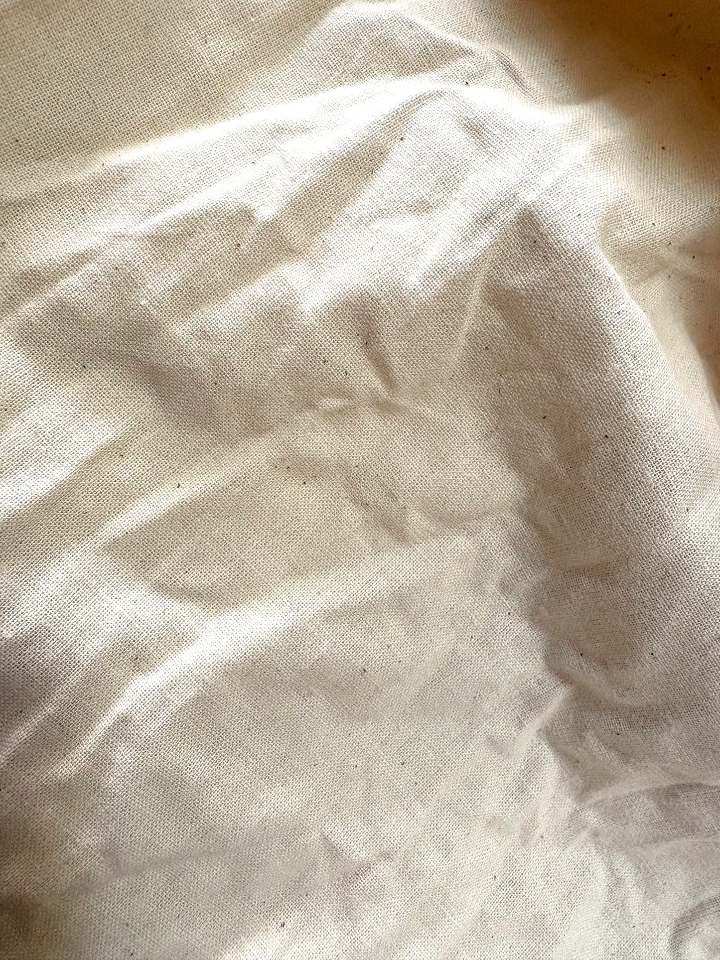 Off-white cotton calico fabric draped in loose crumpled layers.