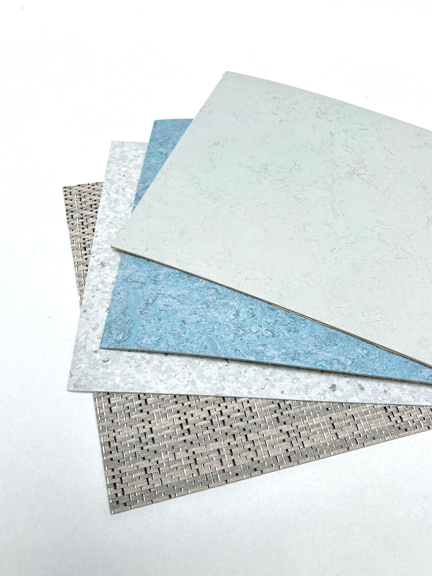 Mixed architectural surface samples are arranged on a white surface