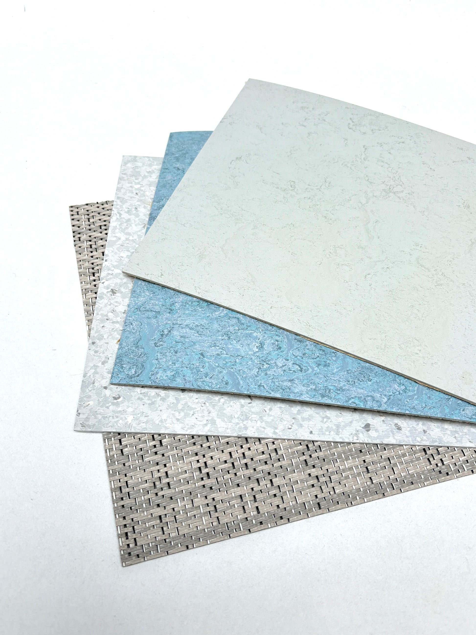 Mixed architectural surface samples are arranged on a white surface