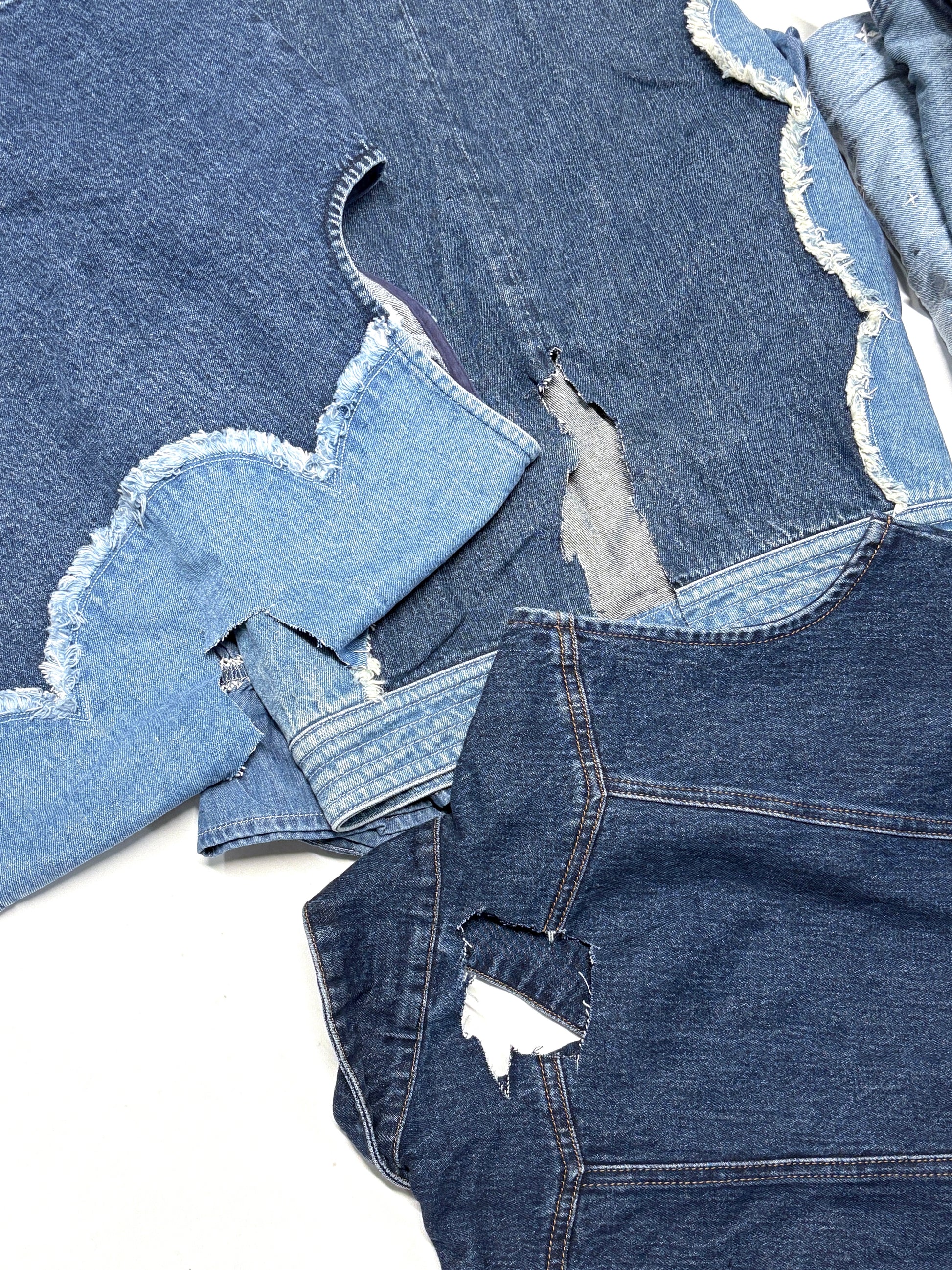 Stack of distressed denim jeans on a white background for upcycling, DIY and crafts projects