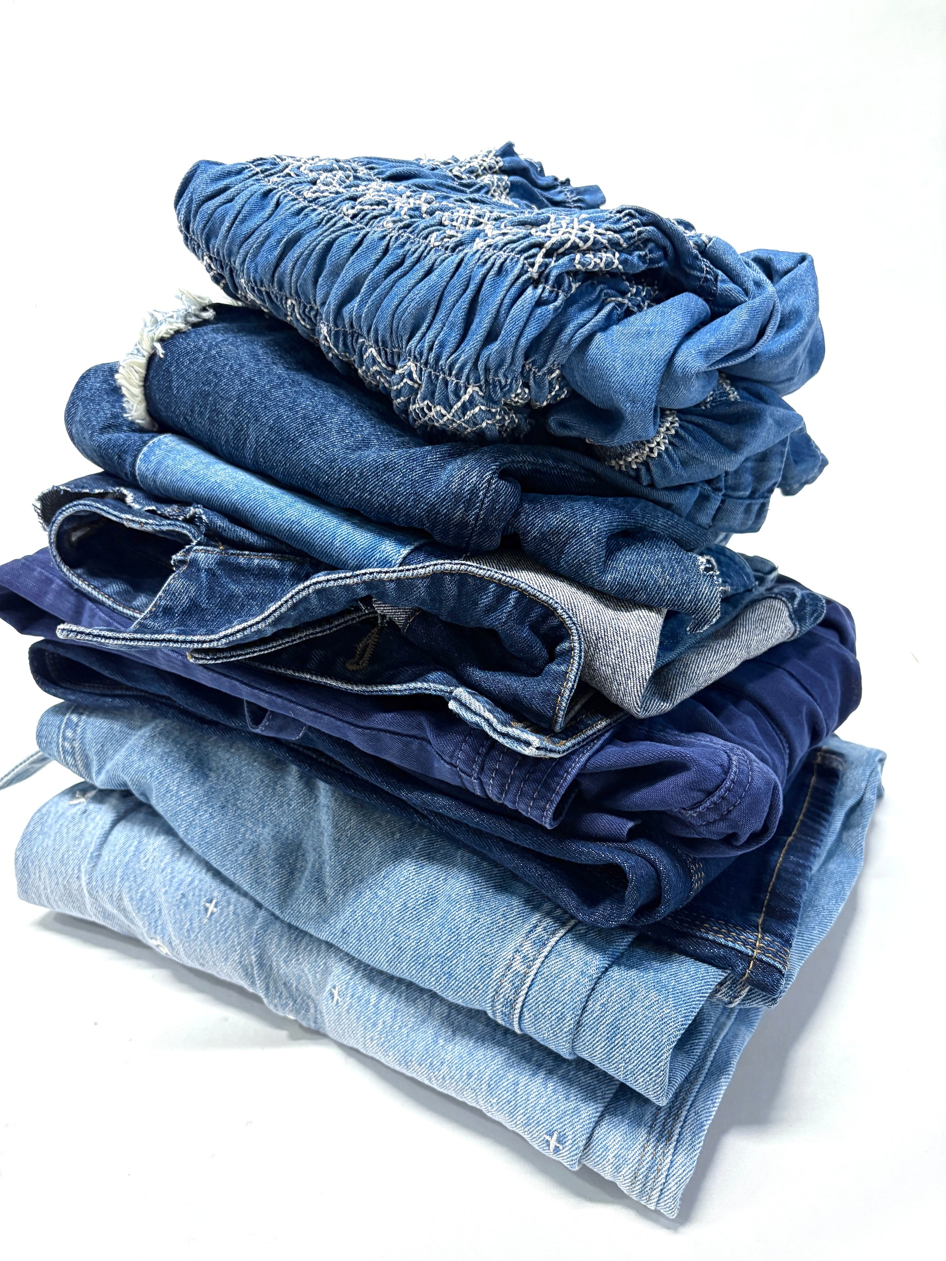Stack of folded denim jeans on a white background