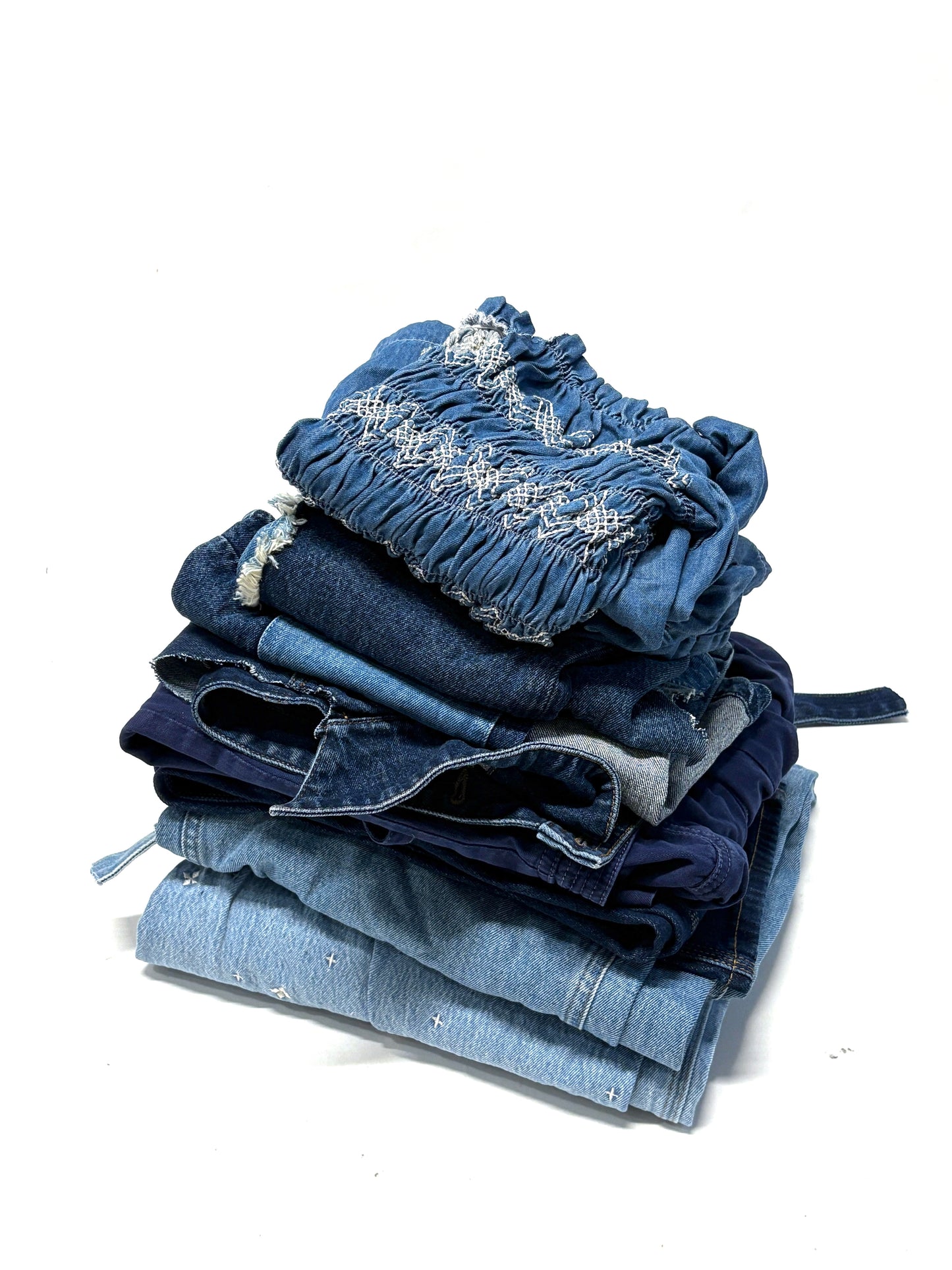 Stack of folded denim jeans on a white background for upcycling and DIY projects