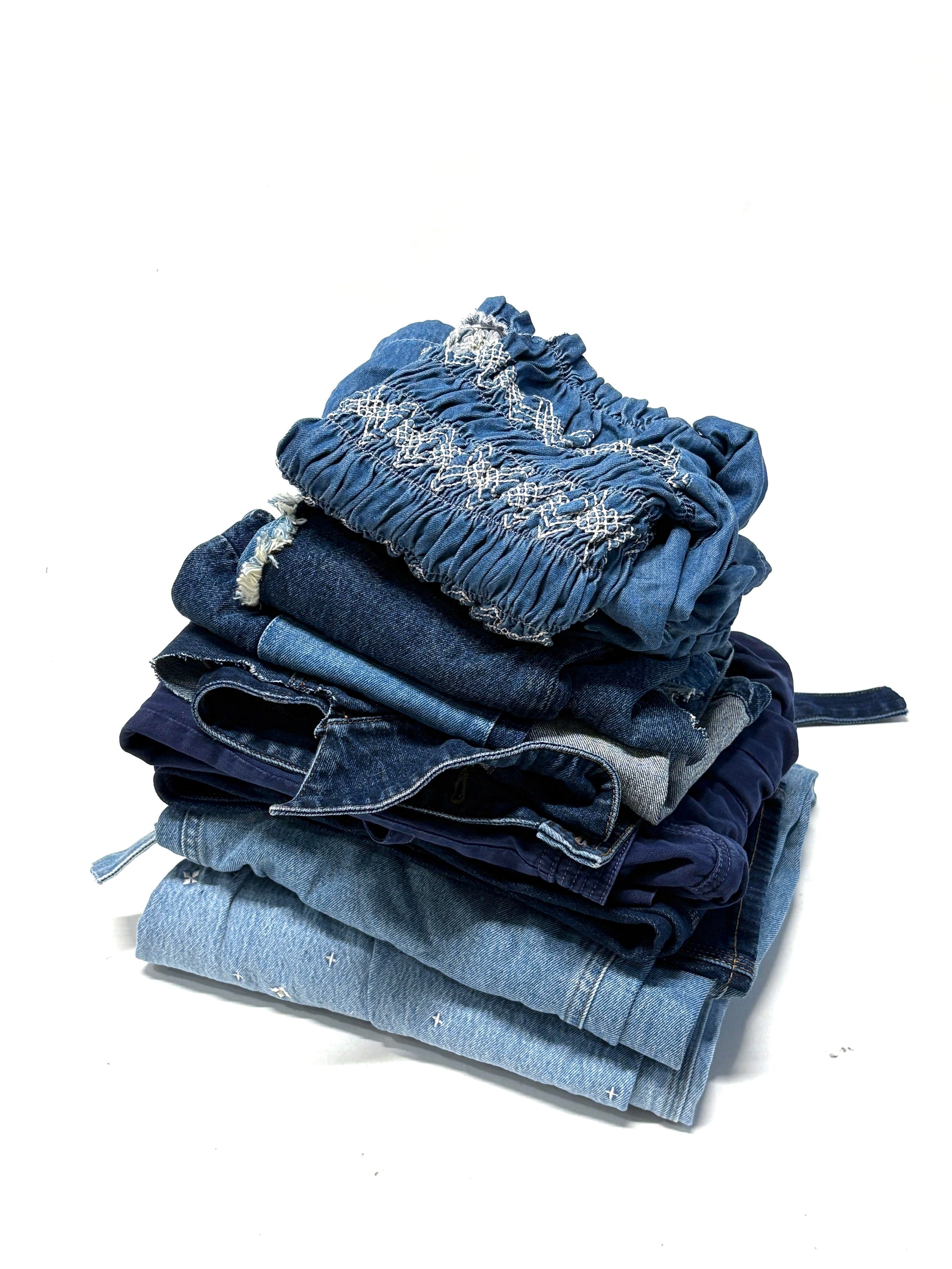Stack of folded denim jeans on a white background for upcycling and DIY projects