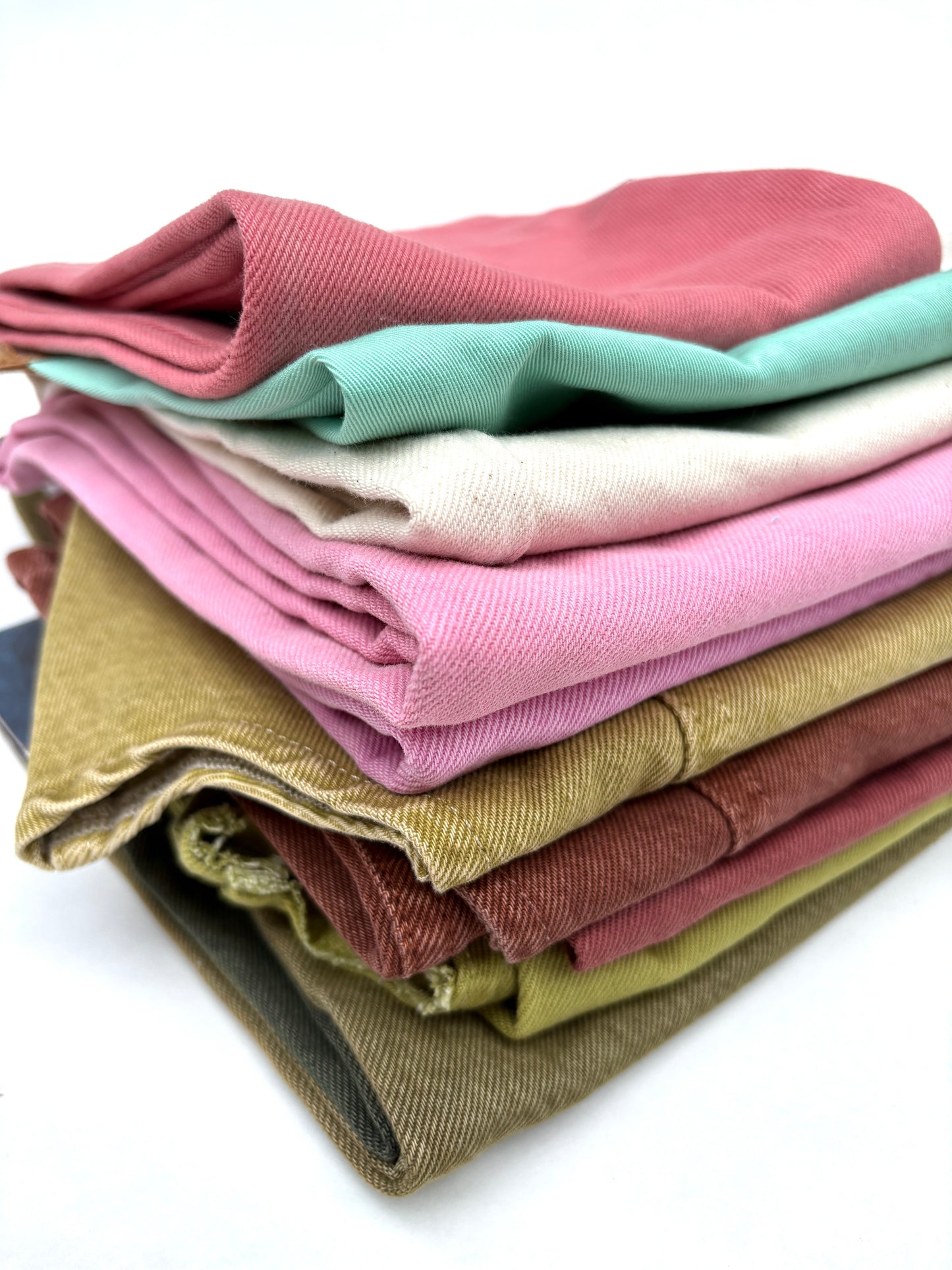 Stack of denim fabric samples in various colours 