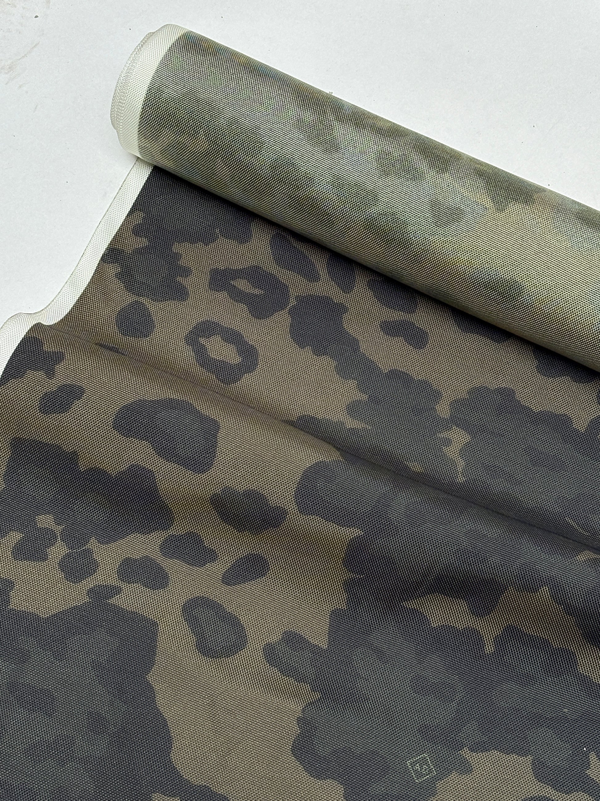 Camouflage patterned fabric arranged in soft folds and creases.