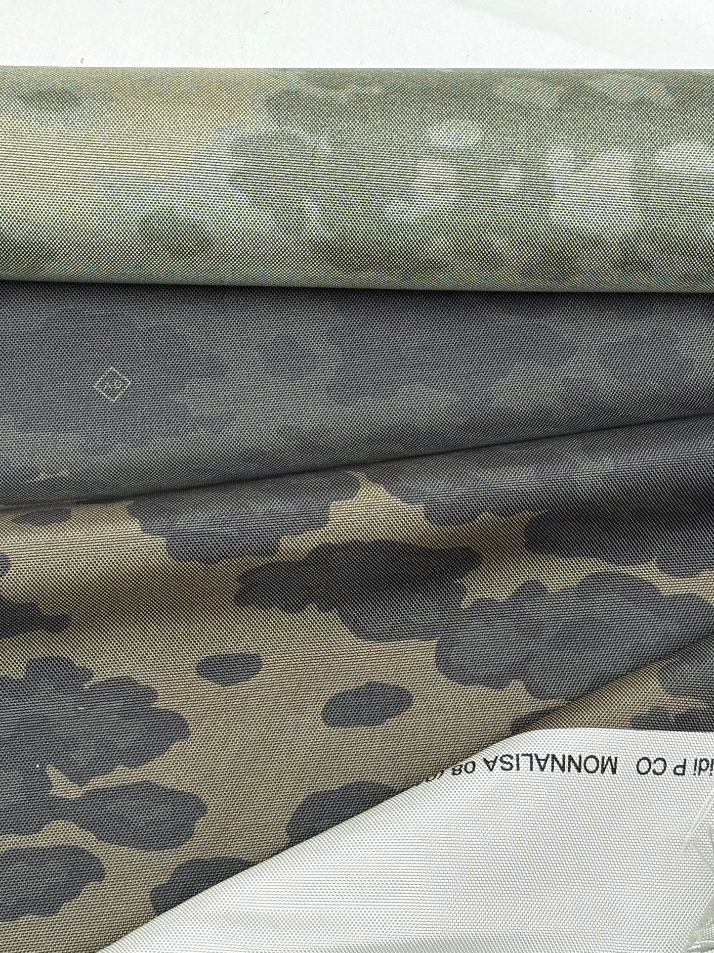 Dark green-khaki fabric gathered to reveal the camouflage print.