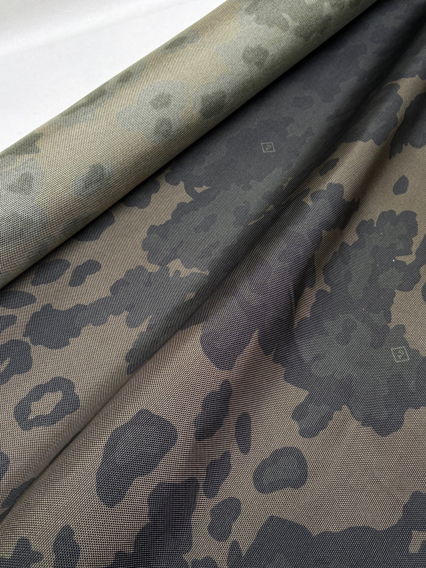 Camouflage patterned fabric shown in a softly crumpled arrangement.