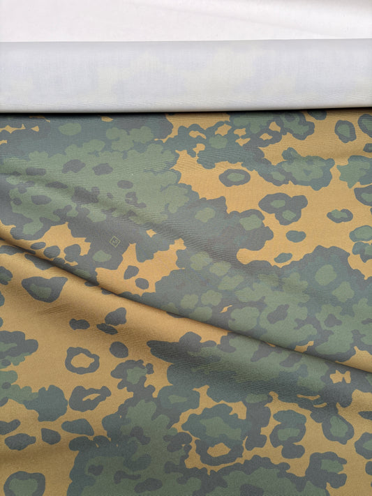 Green and brown camouflage fabric laid flat to show the pattern.