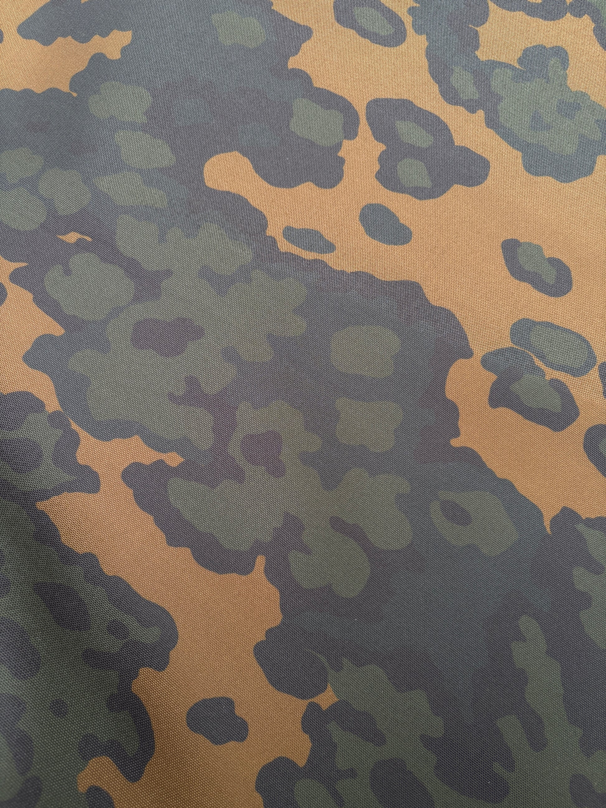 Surface view of green-brown camouflage patterned fabric.