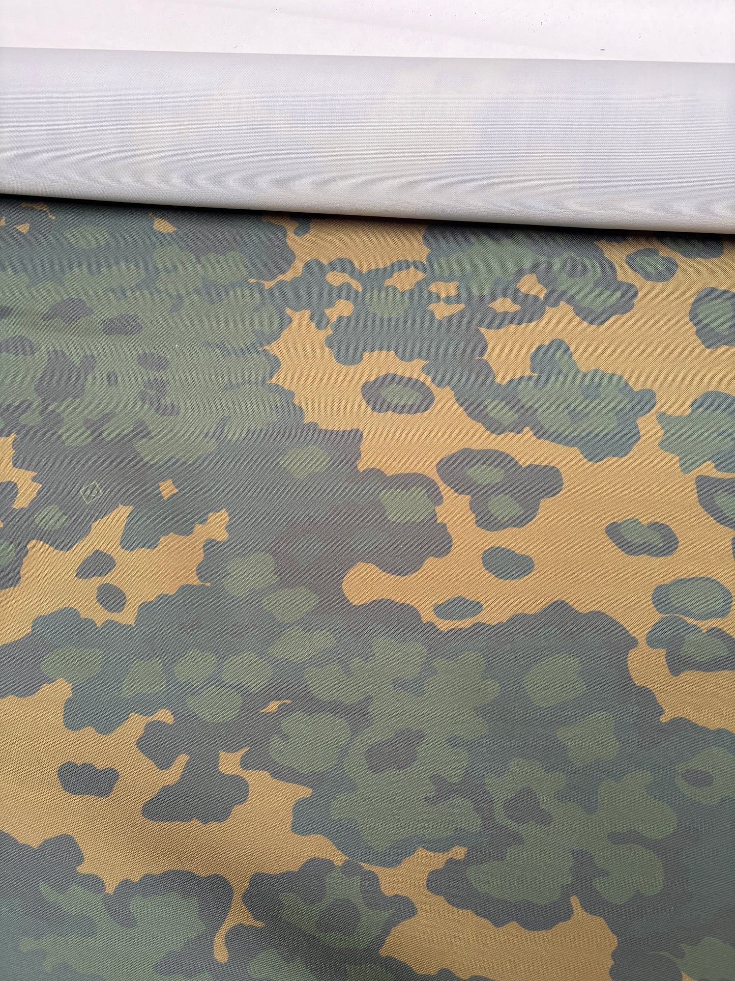 Flat view of camouflage fabric in green and brown tones.