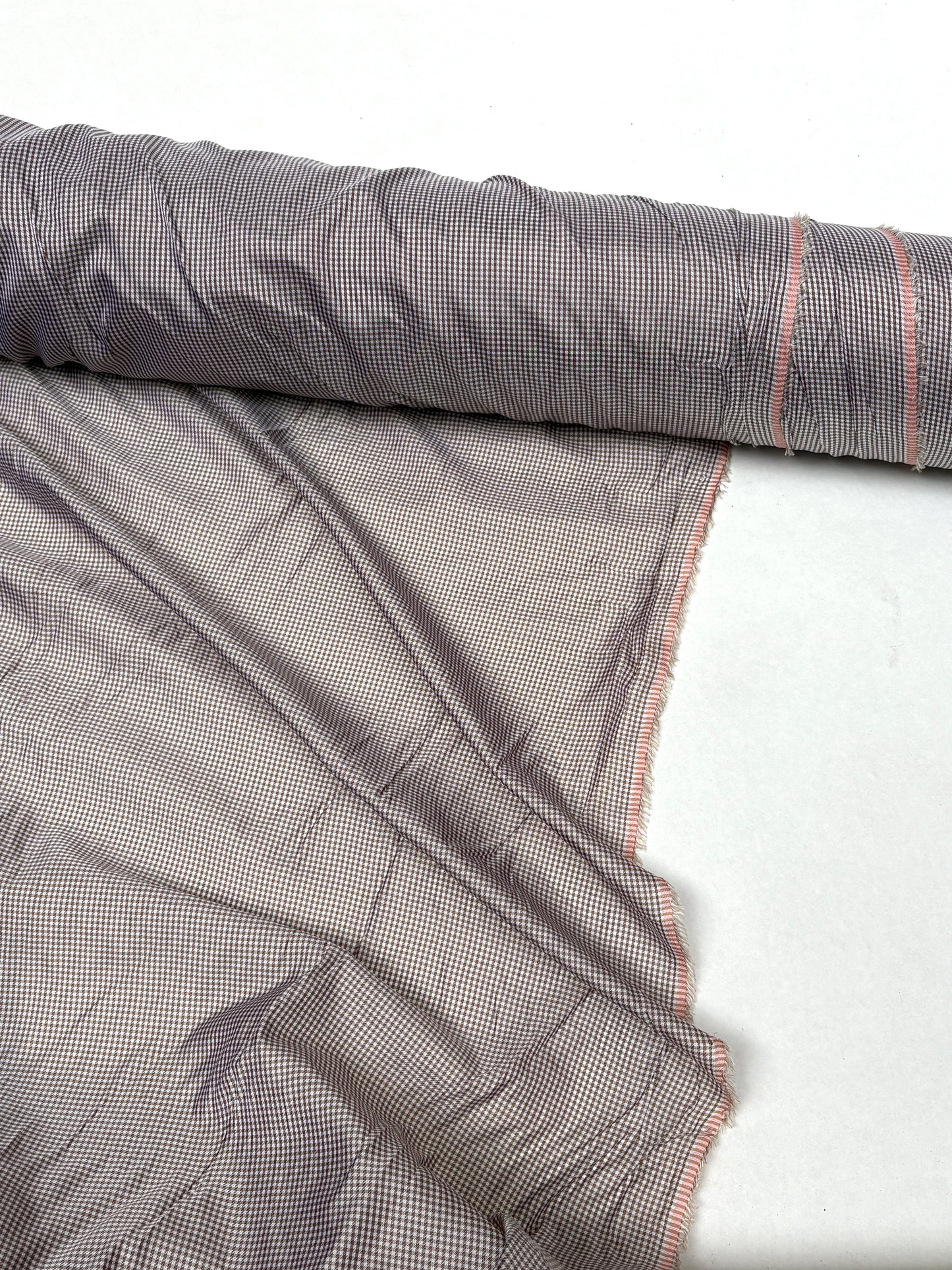 Fine patterned fabric is shown hanging from a rolled edge