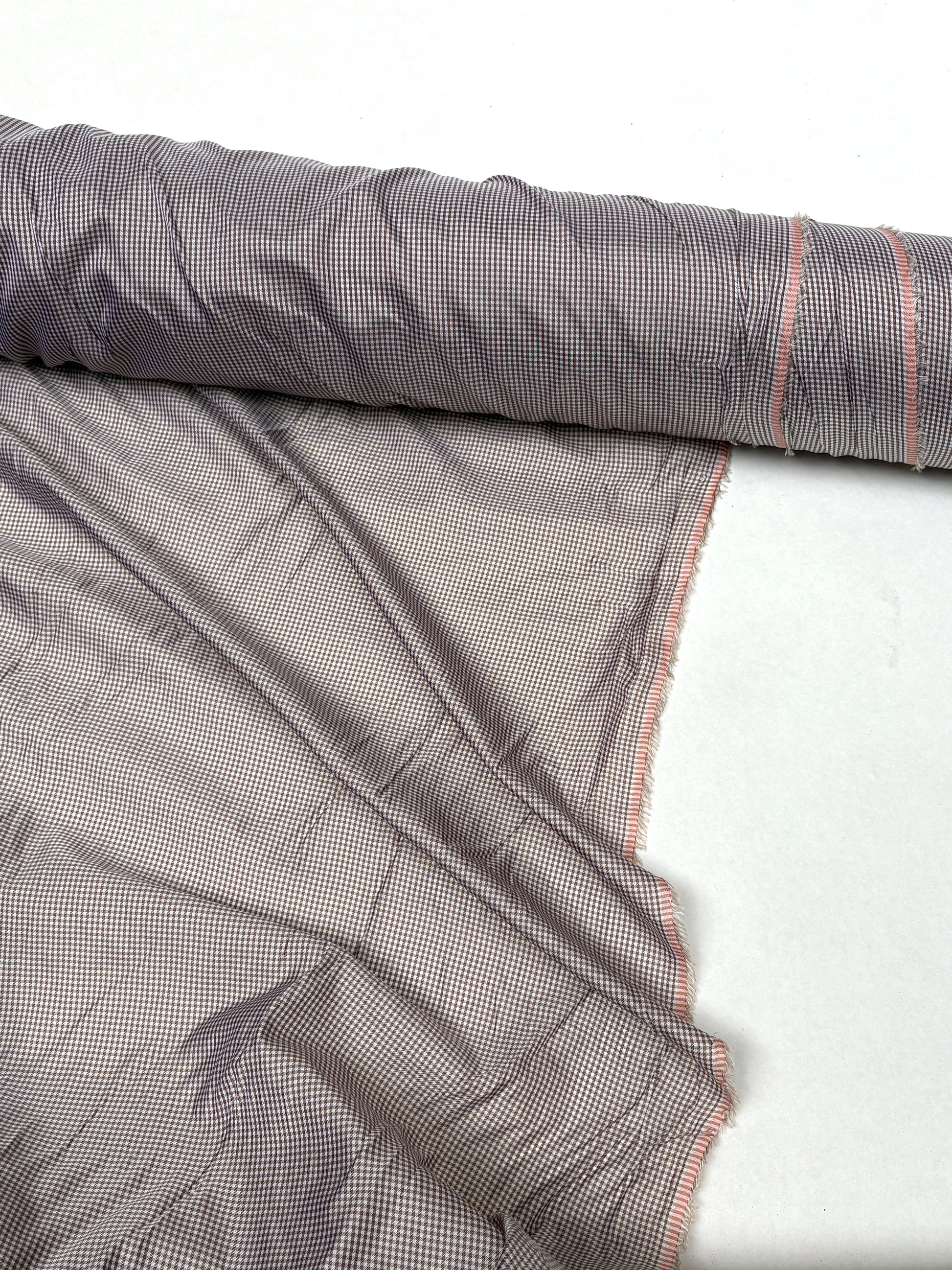 Fine patterned fabric is shown hanging from a rolled edge