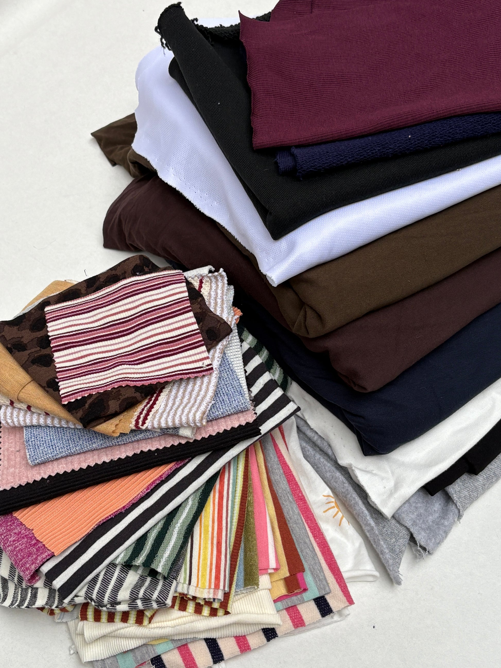 Mixed fabric pieces and patterned swatches layered on a white background.