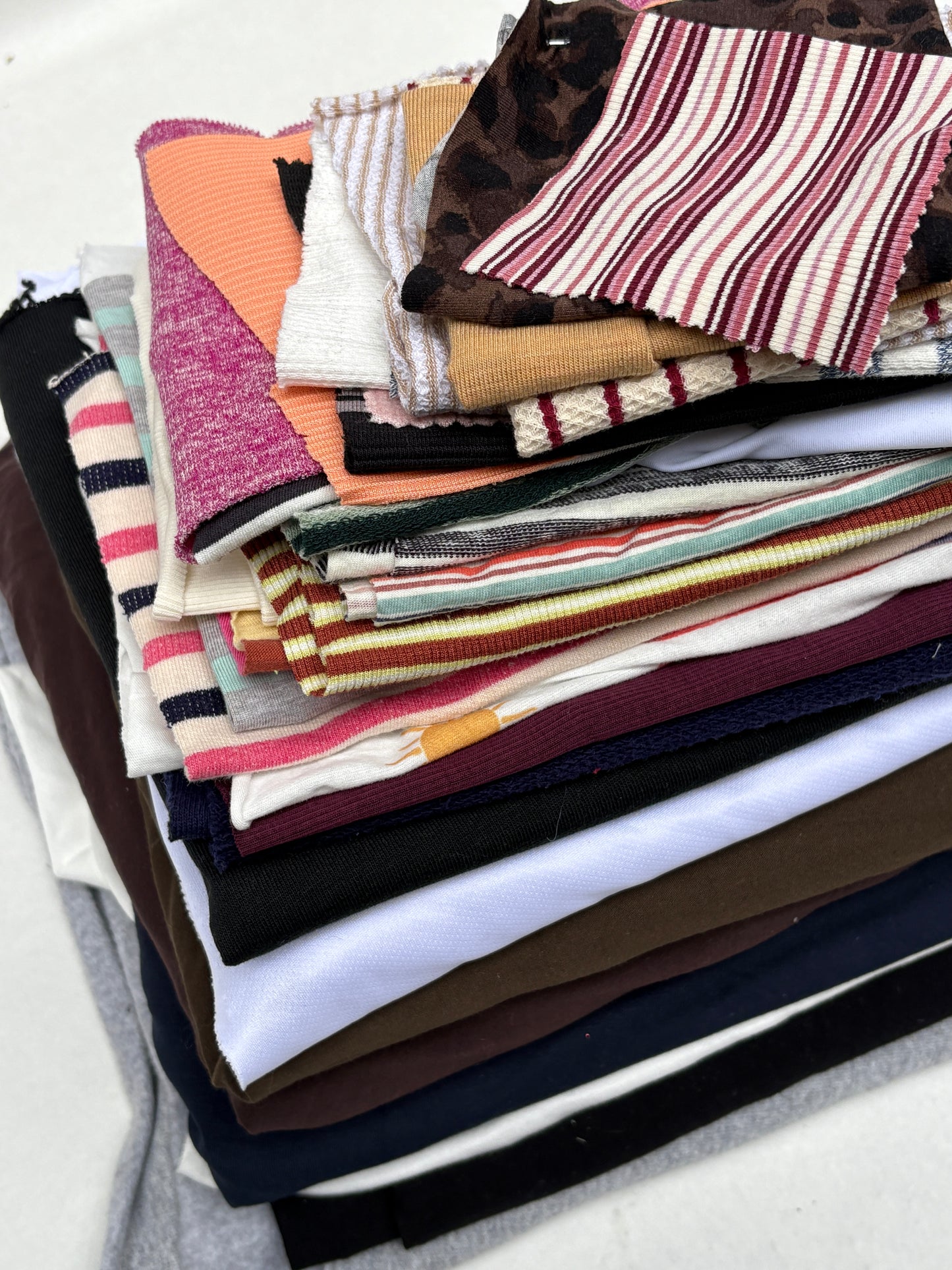 Stacked mixed fabric pieces with assorted striped and patterned swatches on white.