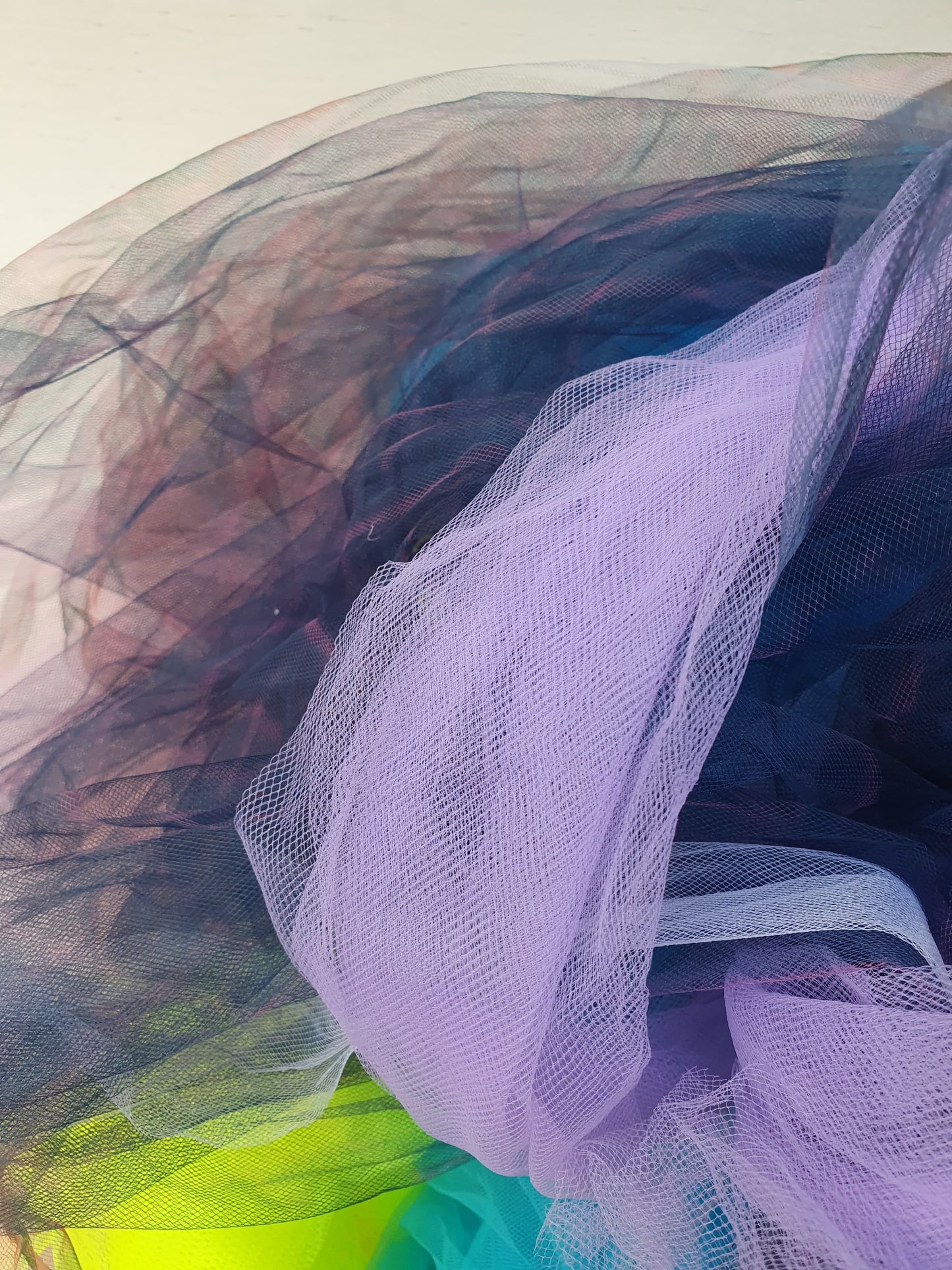 Close-up of layered tulle fabric in lilac, black and bright colour tones.