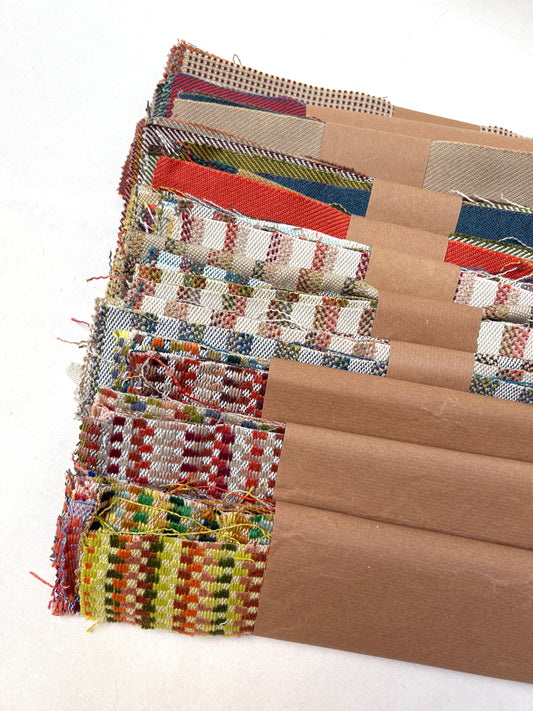 Assorted patterned and plain fabric pieces overlap on a white surface
