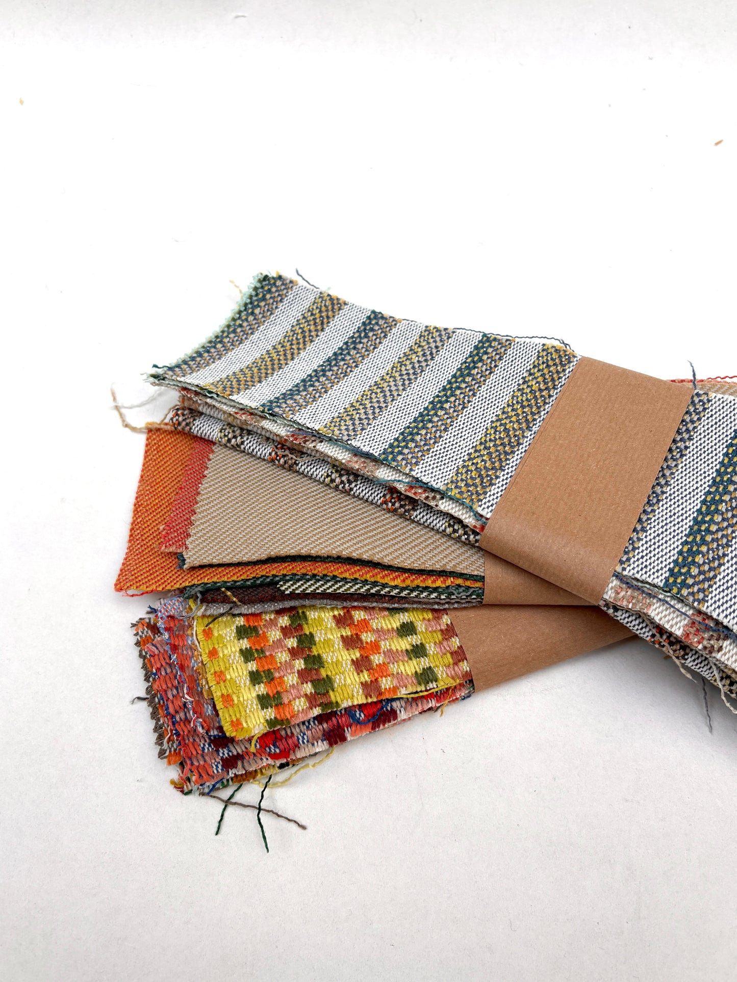 Colourful woven fabric samples are layered beside brown fabric pieces